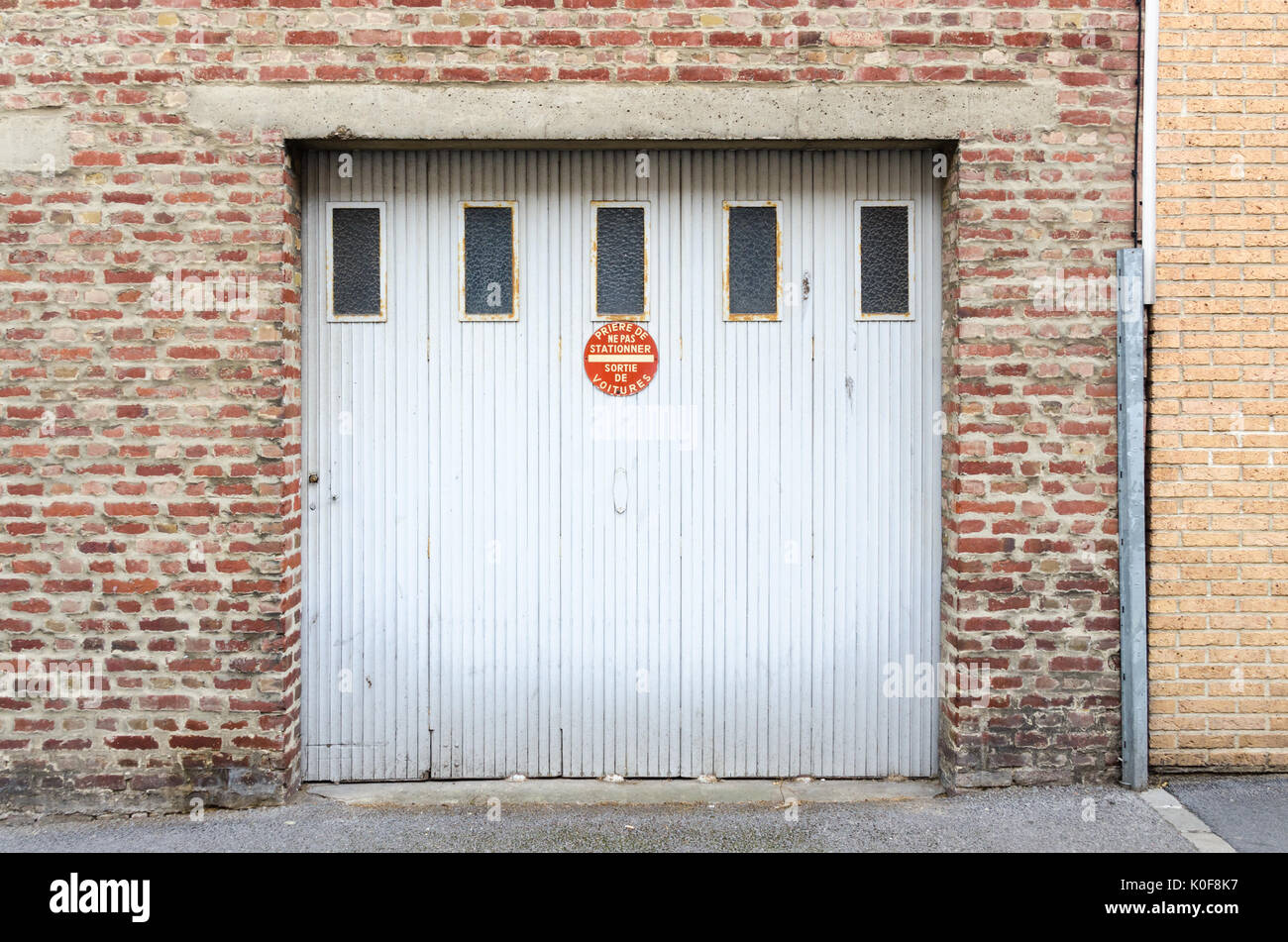 Old White Garage Door With Sign Saying No Parking In French