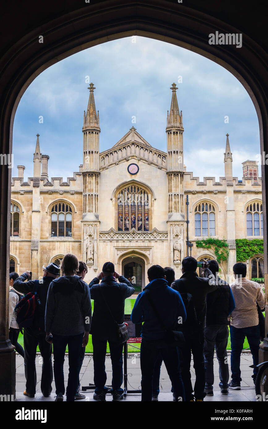 Cambridge tourists, a group of tourists stand under the arched entrance of Corpus Christi College to look at the New Court building, UK. Stock Photo