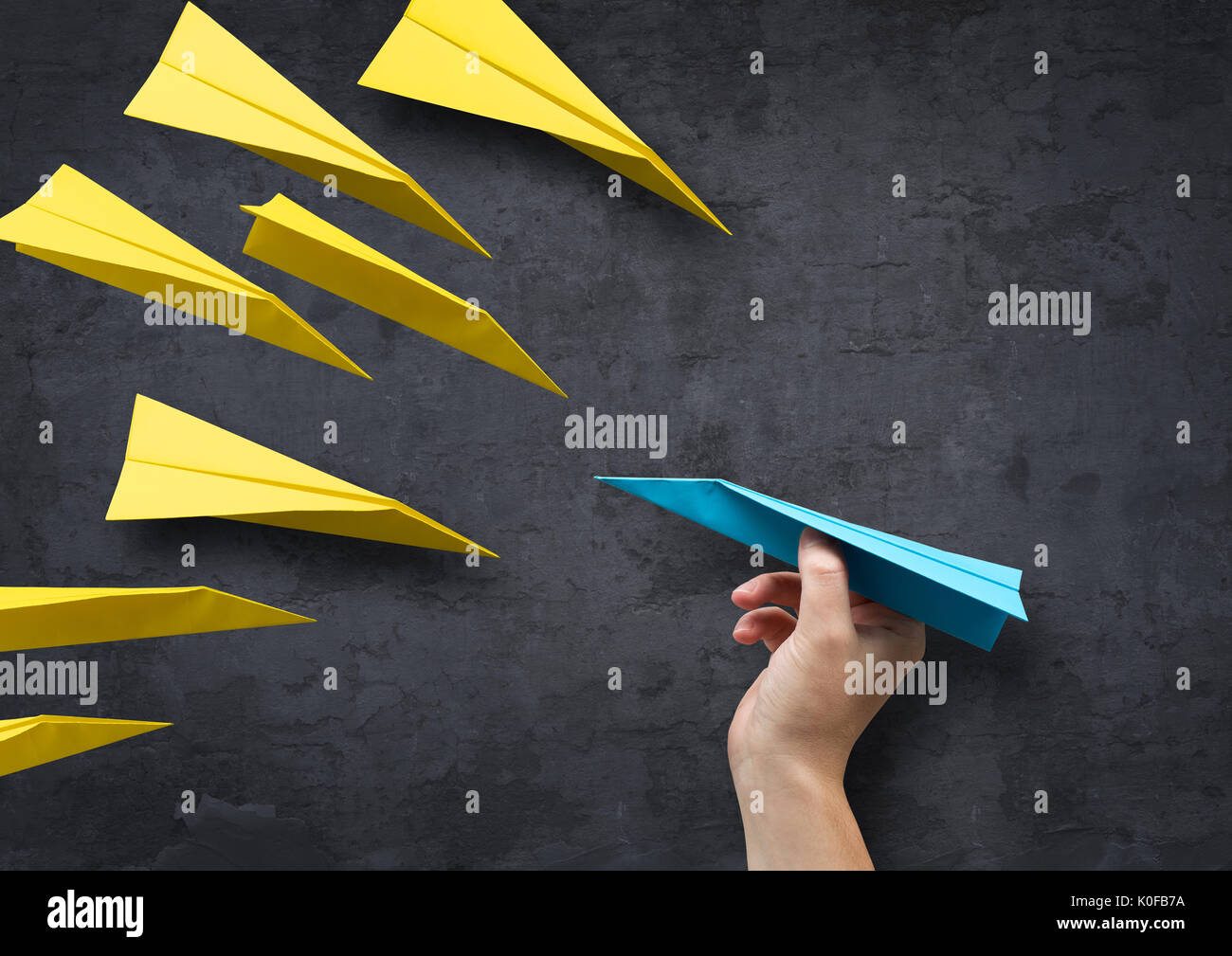 Concept - Being different. A man about to throw a paper plane in a different direction to everyone else. Stock Photo