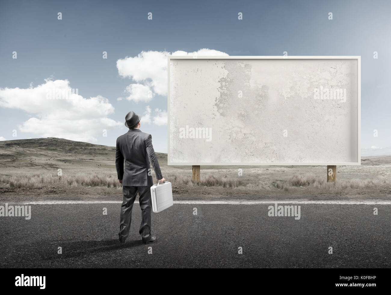 A business man standing and staring at a blank billboard advertisement. Stock Photo