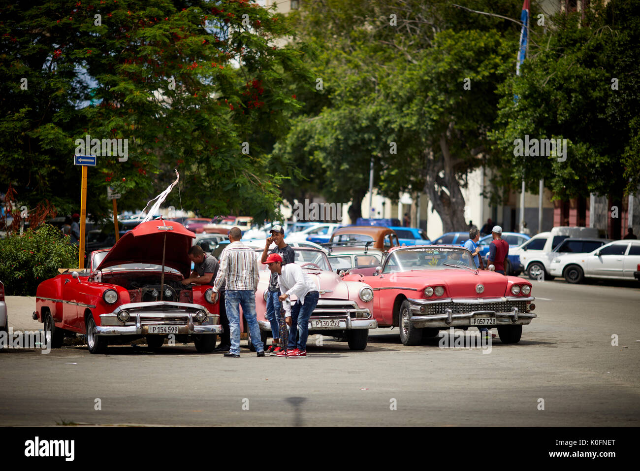 Cuban, Cuba, Capital, Havana Classic old American rerto taxi cars parked one being fixed with its boot up Stock Photo