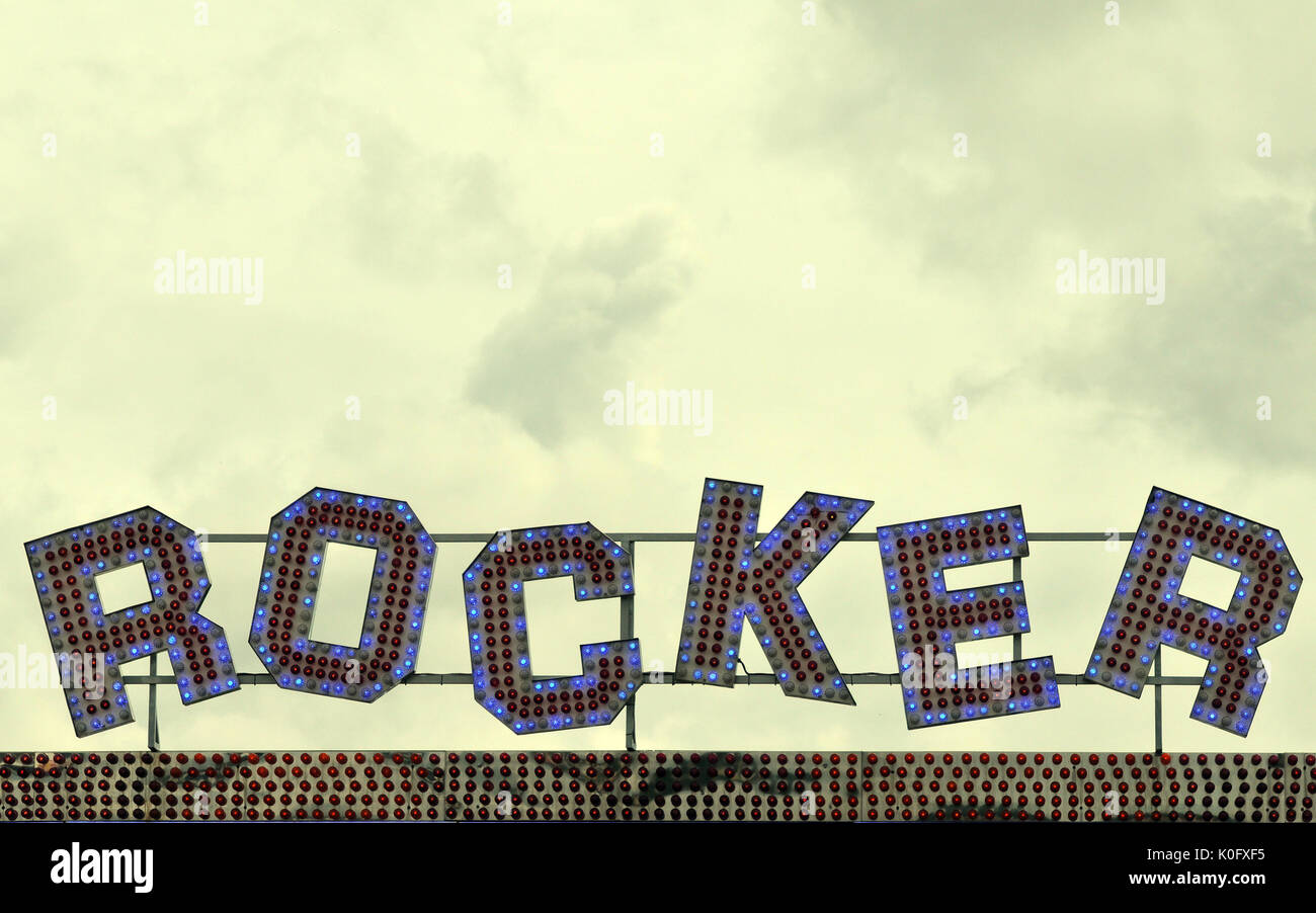 the word rocker above a fairground ride in coloured lights. Illuminated ...