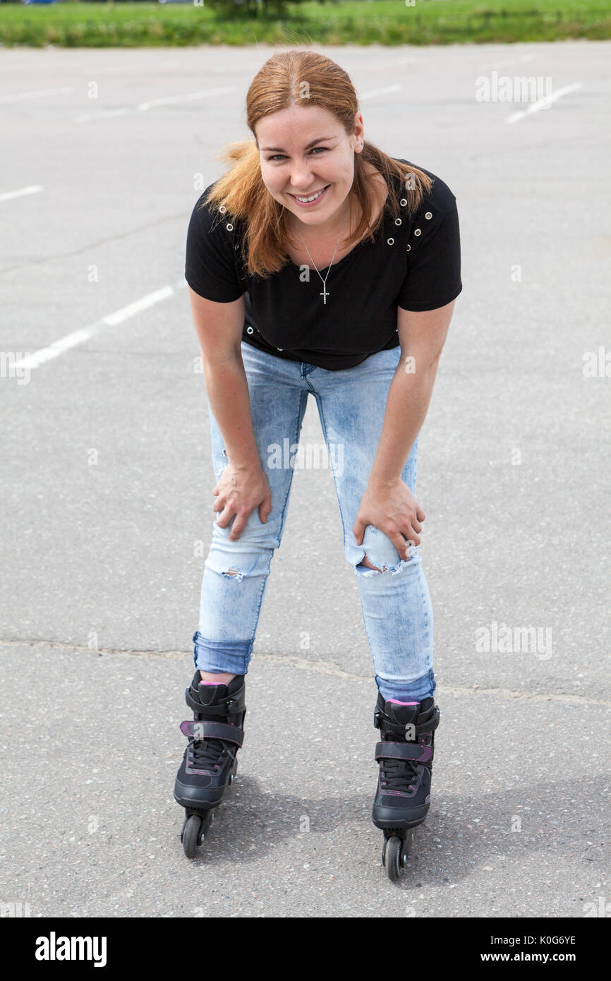 Person Riding Roler Skates Happy and smiling young woman riding on roller-skates in urban park ...
