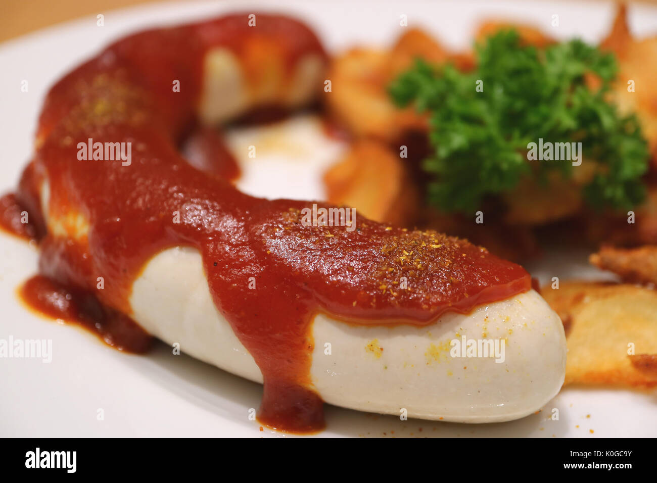 Closed up German white sausage with curry ketchup and fried potatoes, blurred background Stock Photo