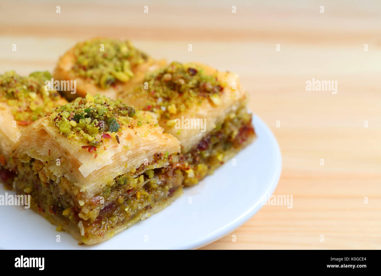 Close-up of Baklava Sweets with Pistachio Nuts Served Wooden Table, Blurred Background Stock Photo