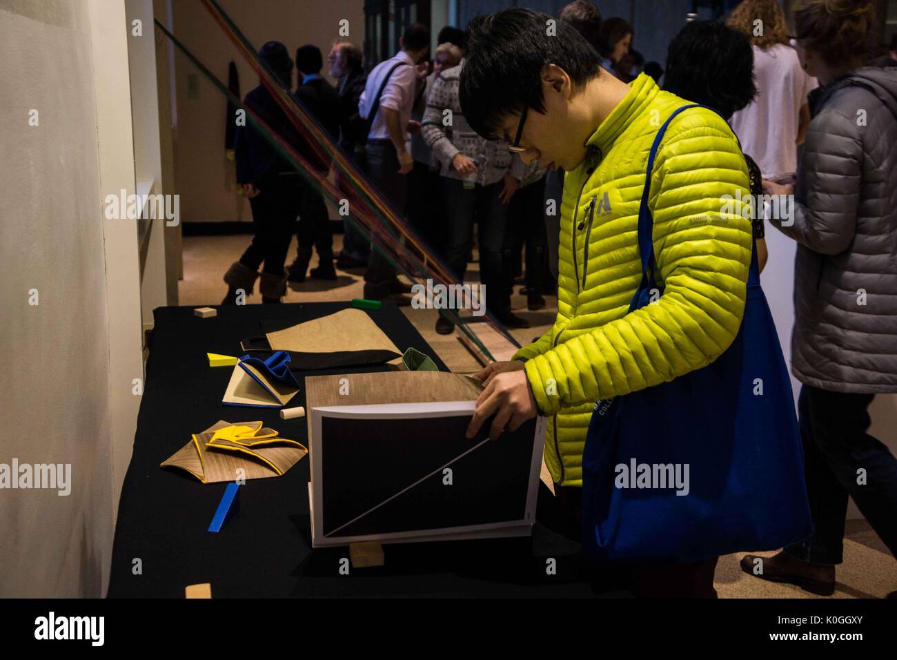 A college student looks down and opens a book on one of the tables at the Unravel the Code Opening at The Johns Hopkins University Sheridan Libraries, 2016. Courtesy Eric Chen. Stock Photo