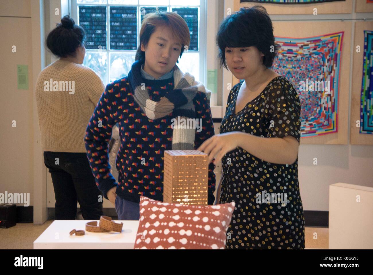 Two attendees look on at a piece of artwork on a table at the Unravel the Code Opening at The Johns Hopkins University Sheridan Libraries, 2016. Courtesy Eric Chen. Stock Photo