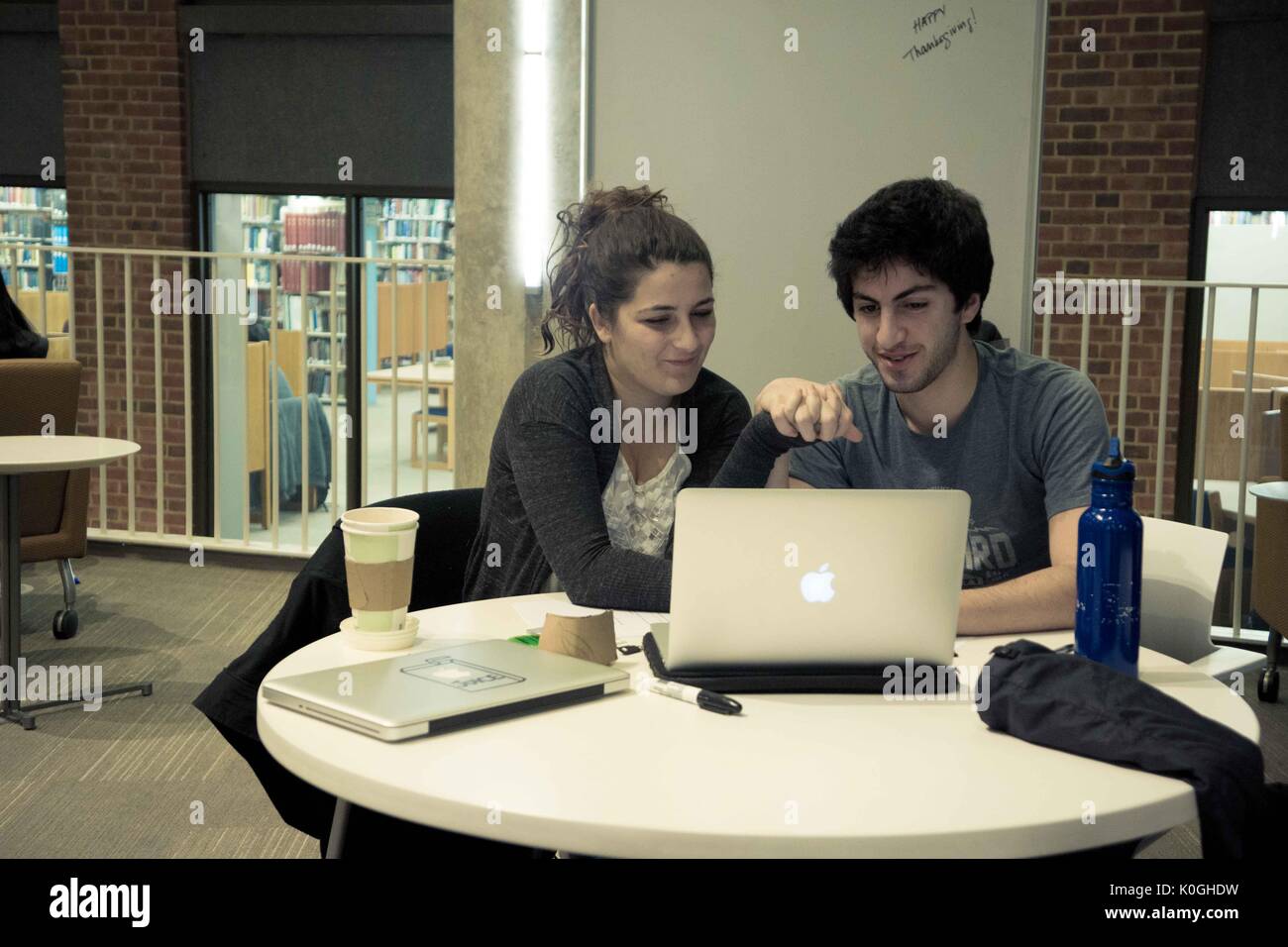 Two college students hold hands and share a laptop screen in the Brody Learning commons, a study space and library on the Homewood campus of the Johns Hopkins University in Baltimore, Maryland, 2015. Courtesy Eric Chen. Stock Photo