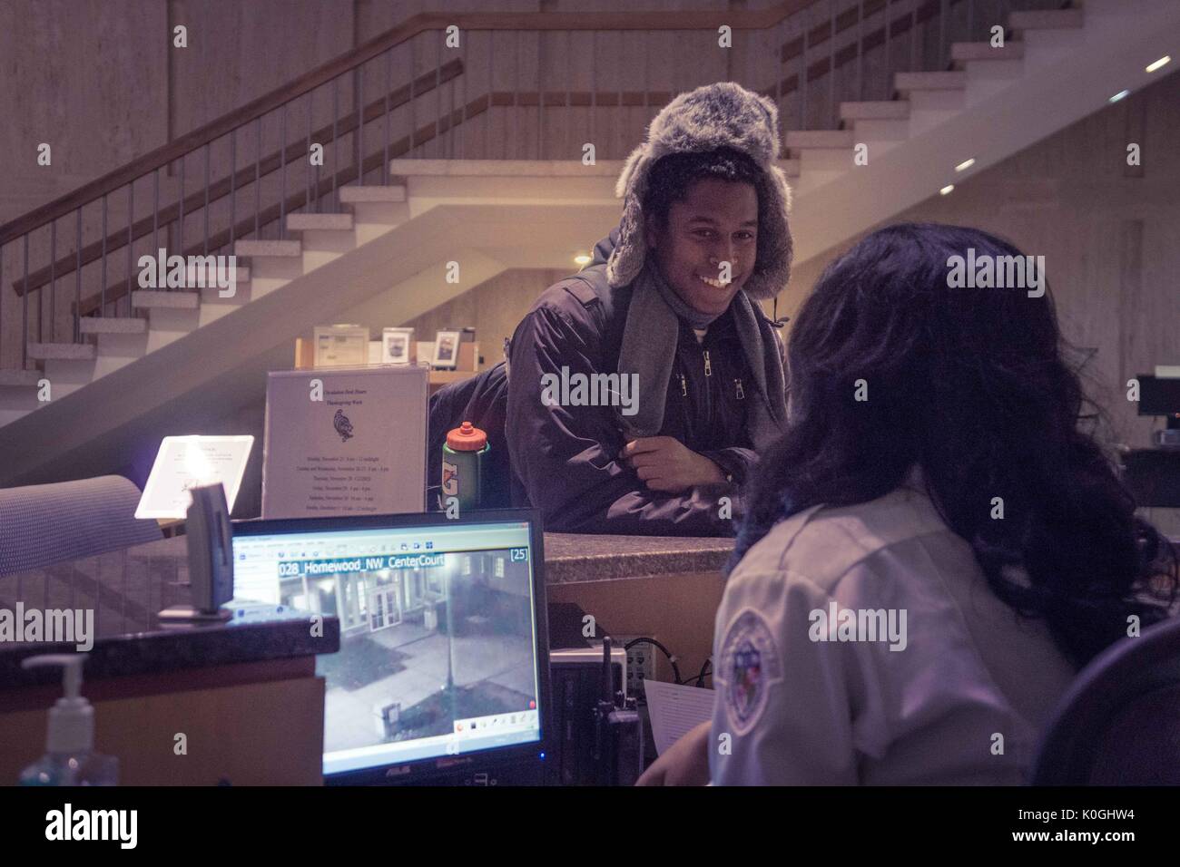 A college student smiles as he talks with a security guard who works at the Milton S. Eisenhower Library on the Homewood campus of the Johns Hopkins University in Baltimore, Maryland, 2014. Courtesy Eric Chen. Stock Photo