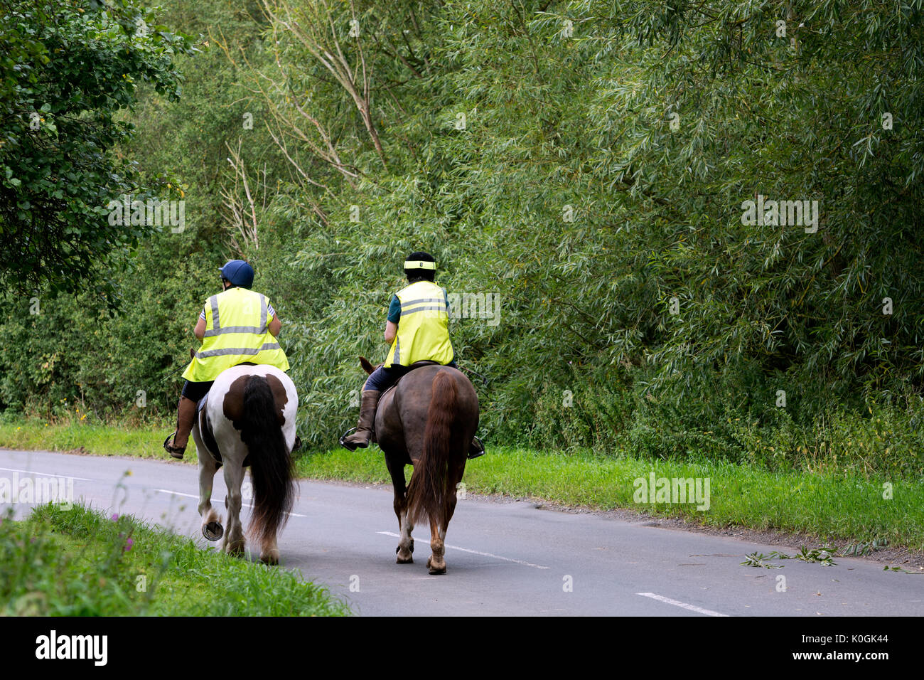 Two women riding horses on a country road, Warwickshire, UK Stock Photo