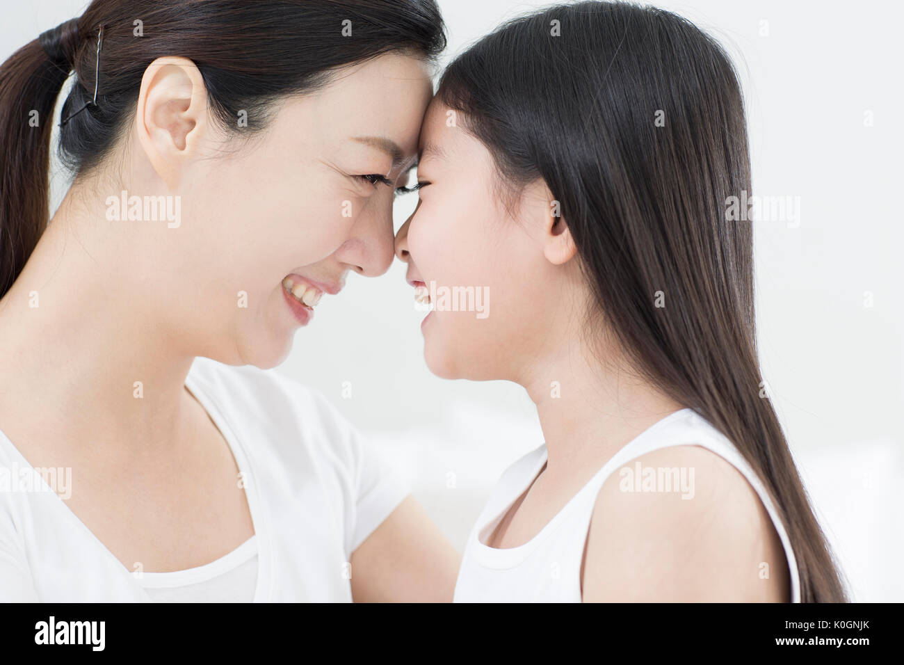 Side view portrait of smiling mother and daughter face to face Stock Photo