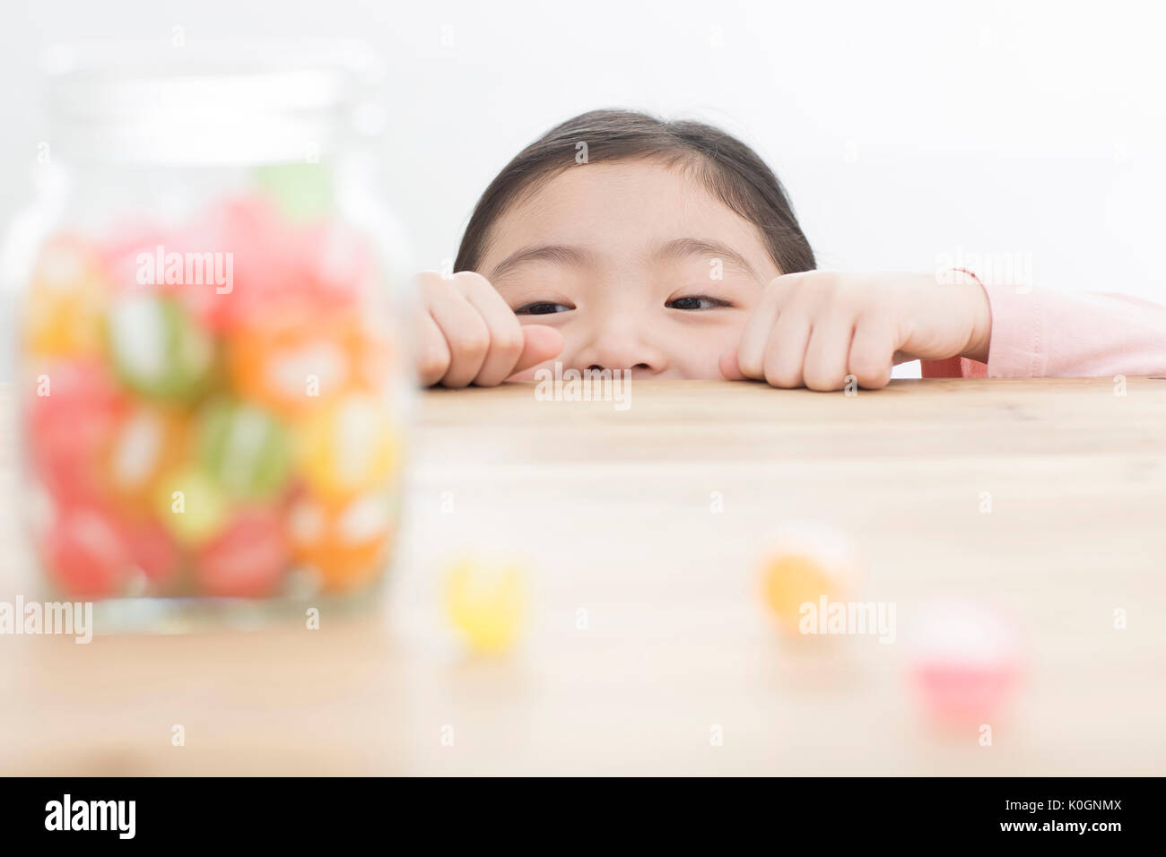 Smiling girl watching candies in a jar Stock Photo
