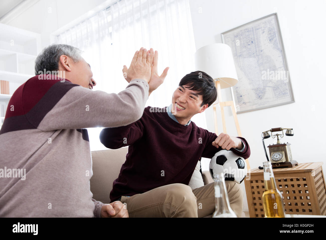 Smiling senior man and his young son slapping high five Stock Photo
