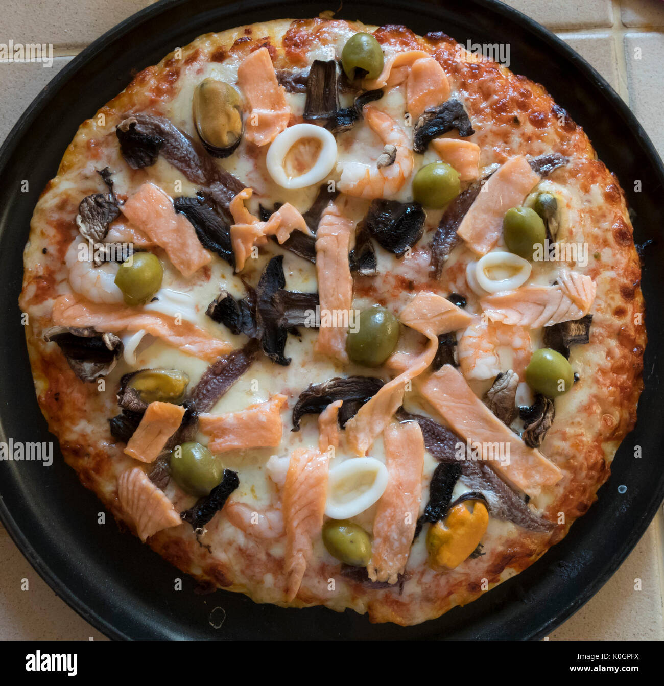 Seafood pizza with salmon, prawns, squid rings, olives Stock Photo