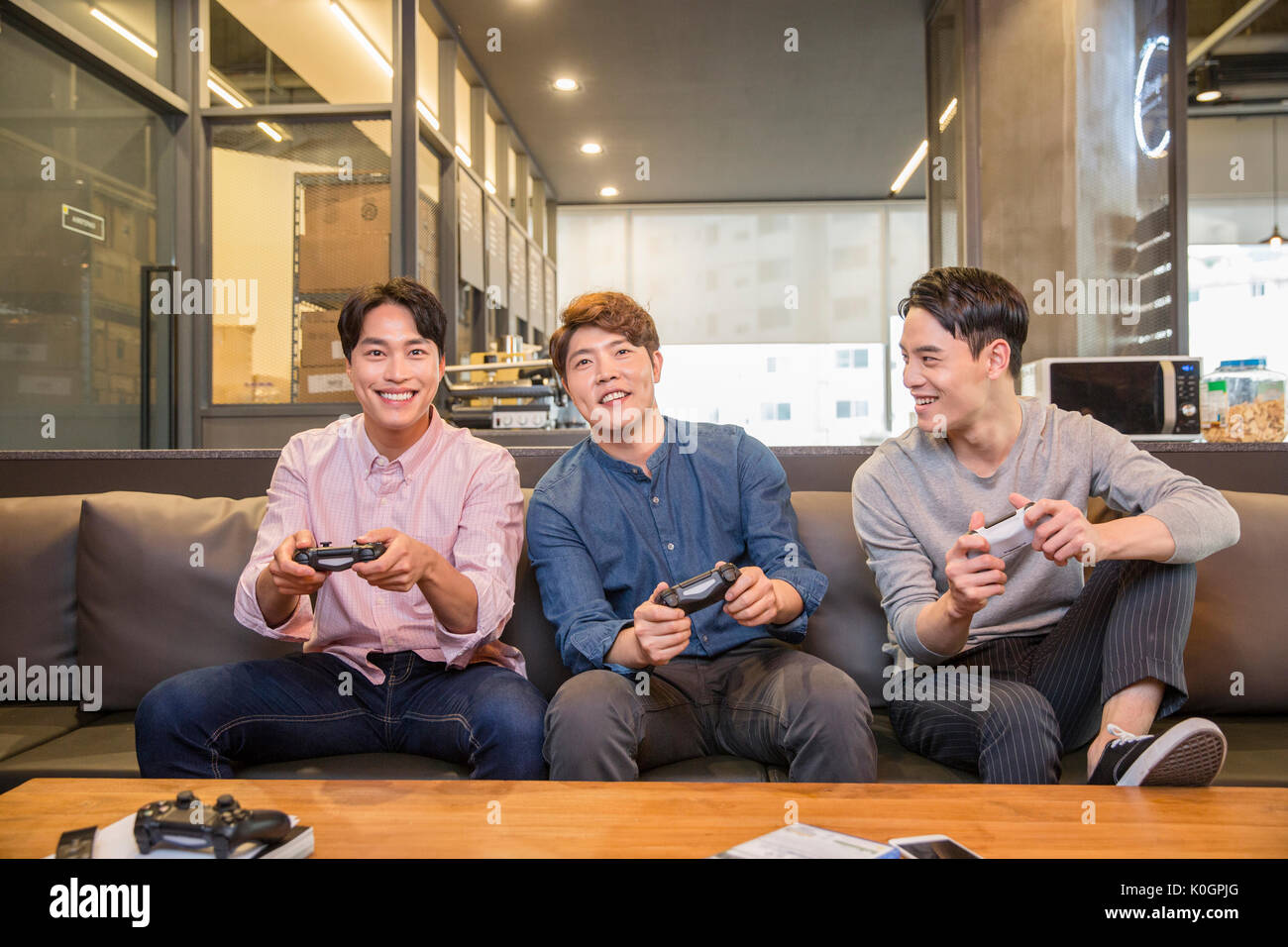 Three smiling coworkers playing video games Stock Photo