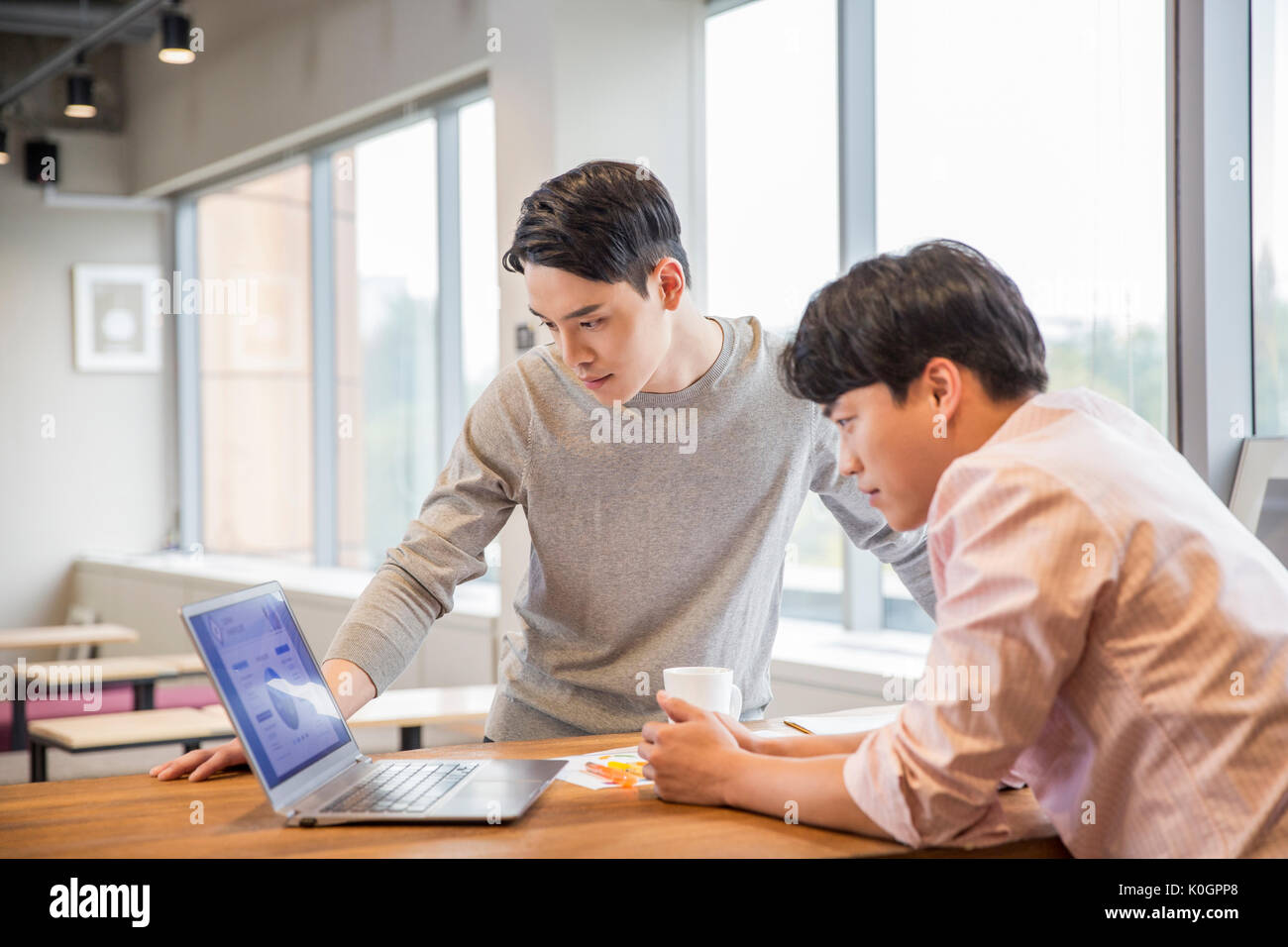 Side view of two businessmen sharing a notebook computer at office Stock Photo