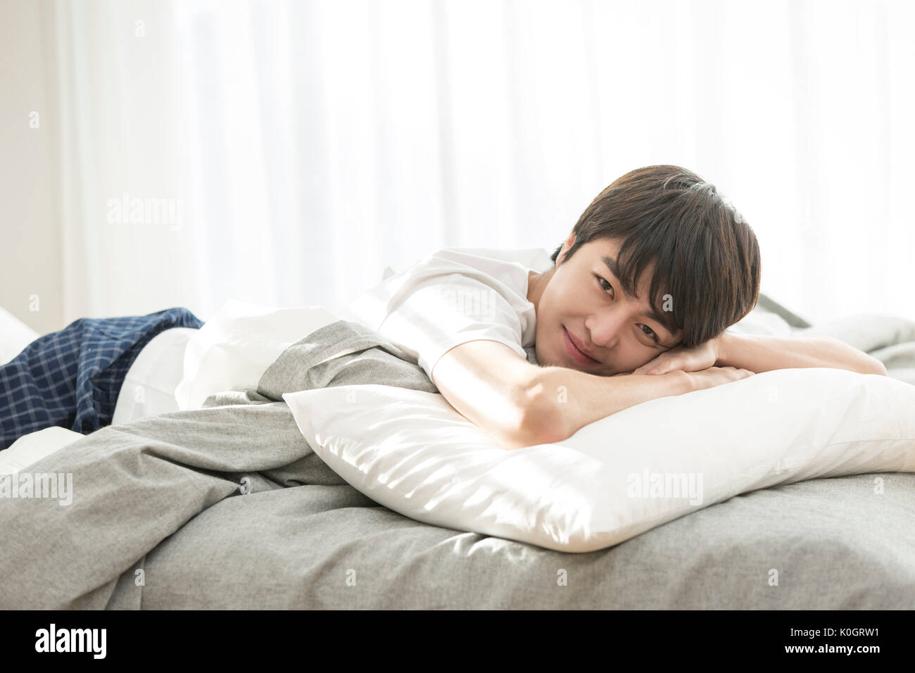 Smiling single man lying face down on bed Stock Photo Alamy