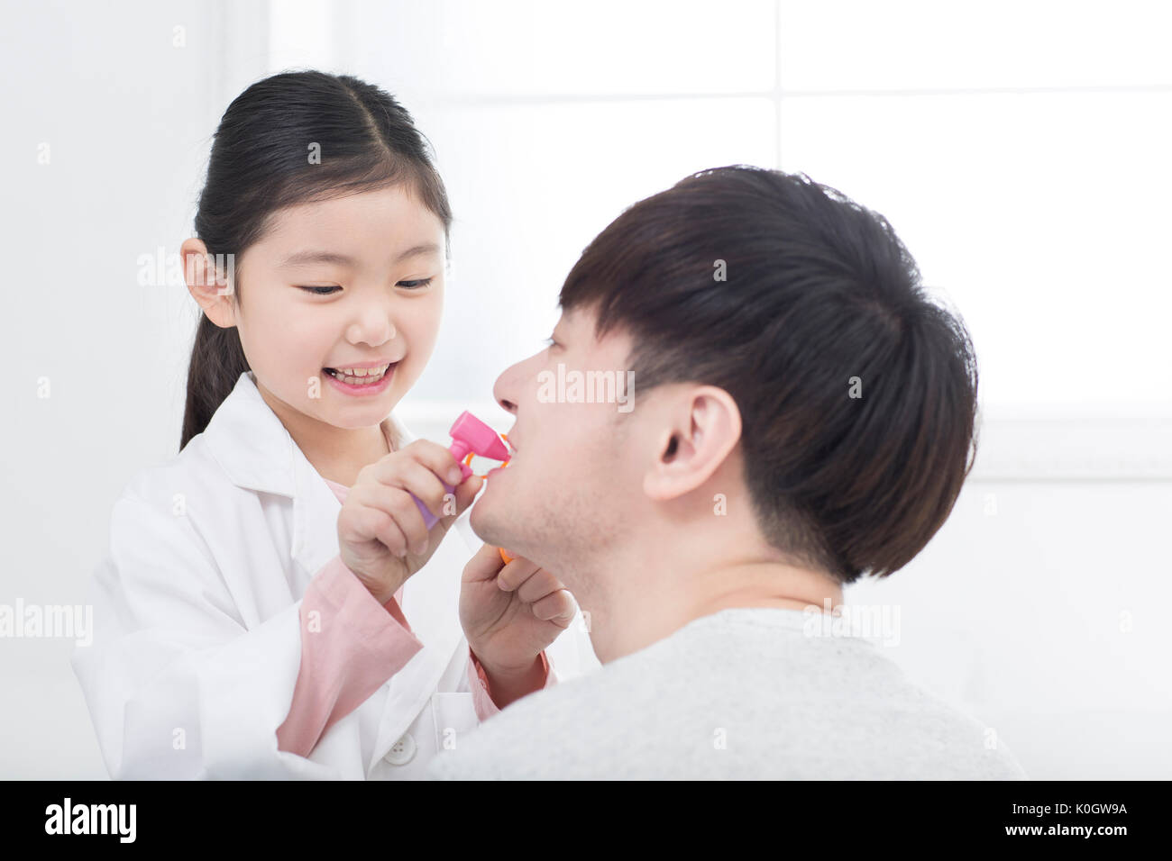 Smiling girl and her father playing hospital Stock Photo
