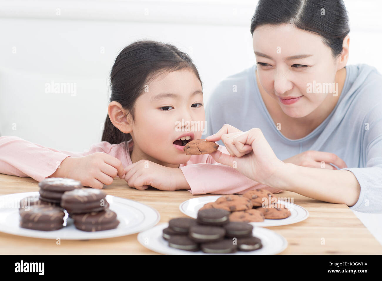 Portrait of smiling mother and her daughter having sweet cookies Stock Photo