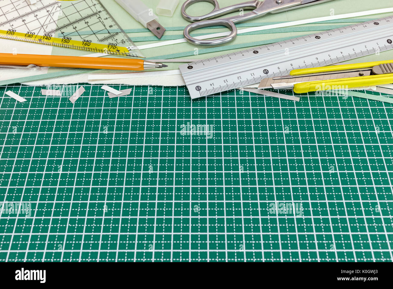 new green cutting mat with metal ruler, yellow cutter, pencil and