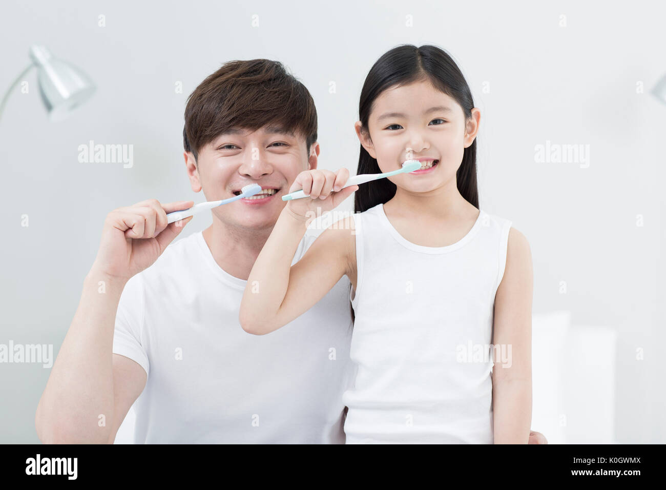 Portrait of smiling father and daughter brushing teeth together Stock Photo