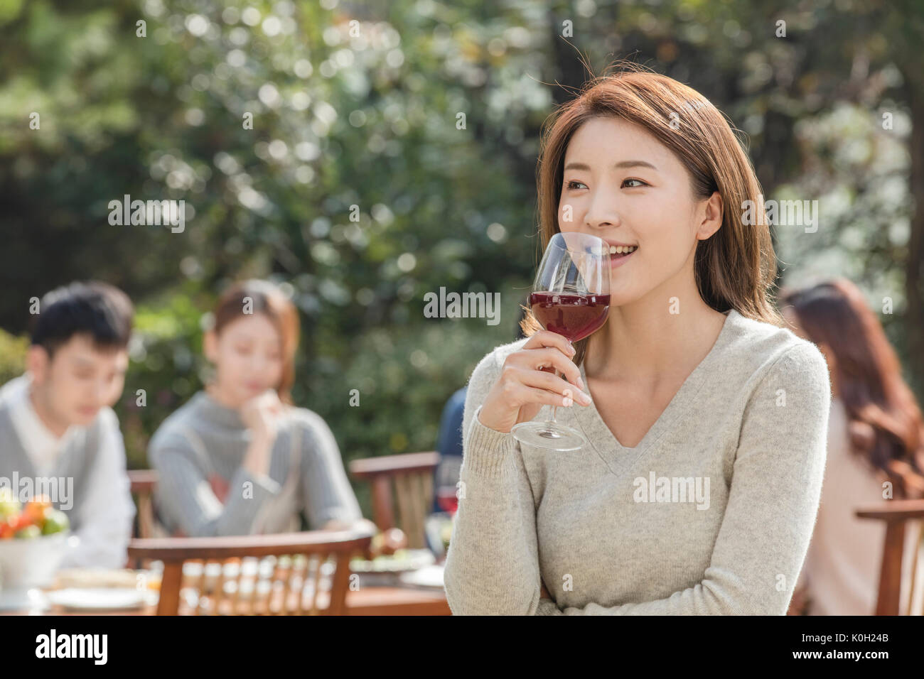 Portrait of young smiling woman holding a glass of wine at garden party Stock Photo