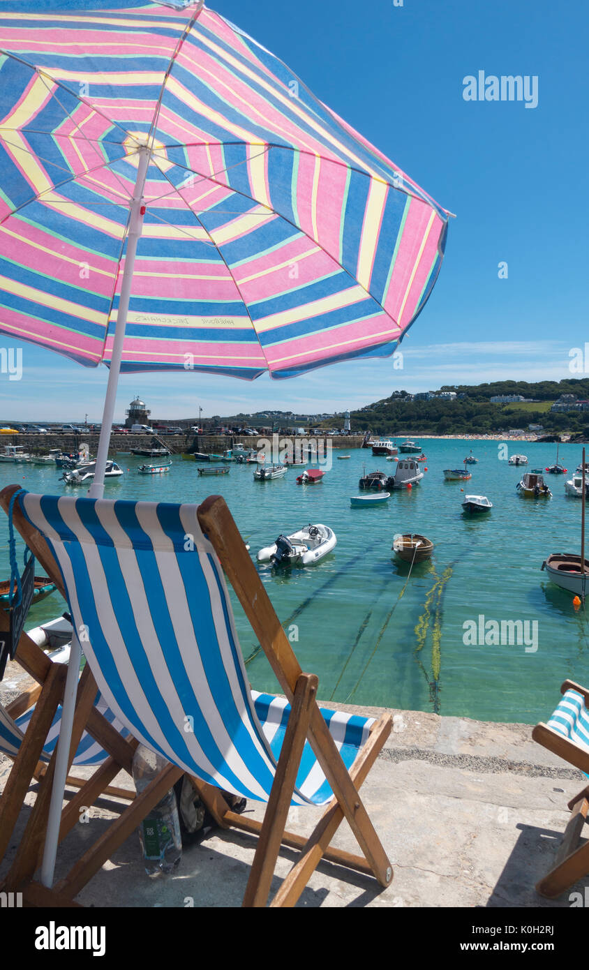 St. Ives harbour deckchair and colourful sun shade umbrella, Cornwall England UK Stock Photo