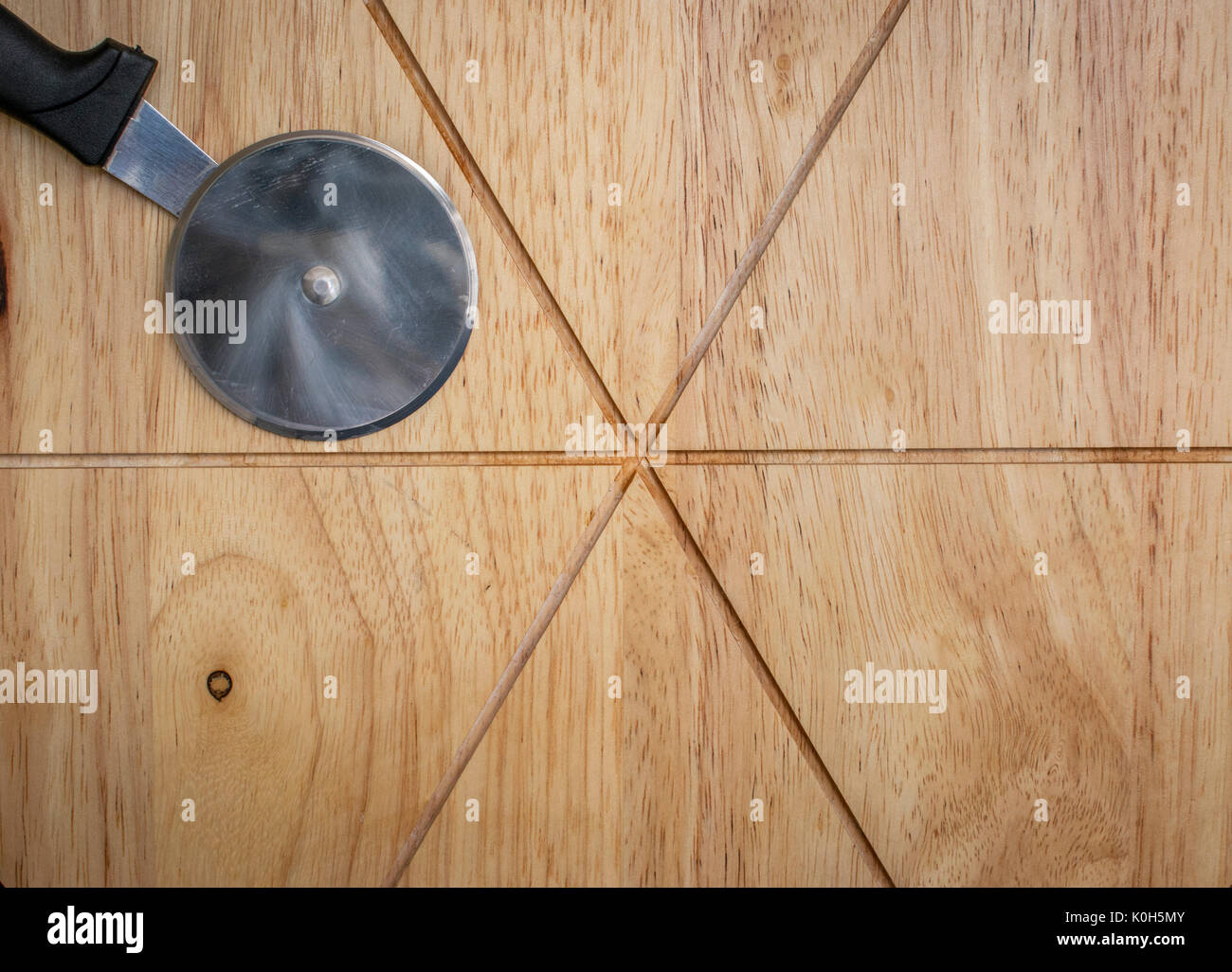 Pizza cutter roller knife on top of a pizza cutting board Stock Photo