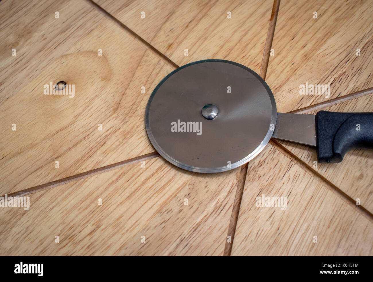 Pizza cutter roller knife on top of a pizza cutting board Stock Photo