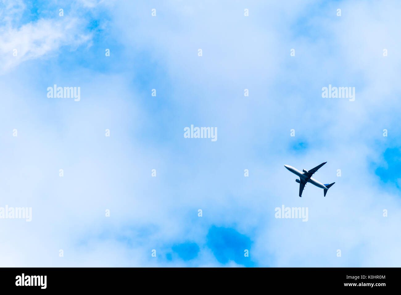 Big airplane in air on blue sky. View of flying aeroplane from bottom, from ground. Stock Photo