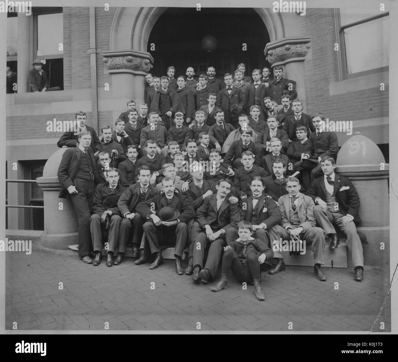 Group portrait of the Johns Hopkins University class of 1890, gathered on the steps to a large brick building. 1890. Stock Photo