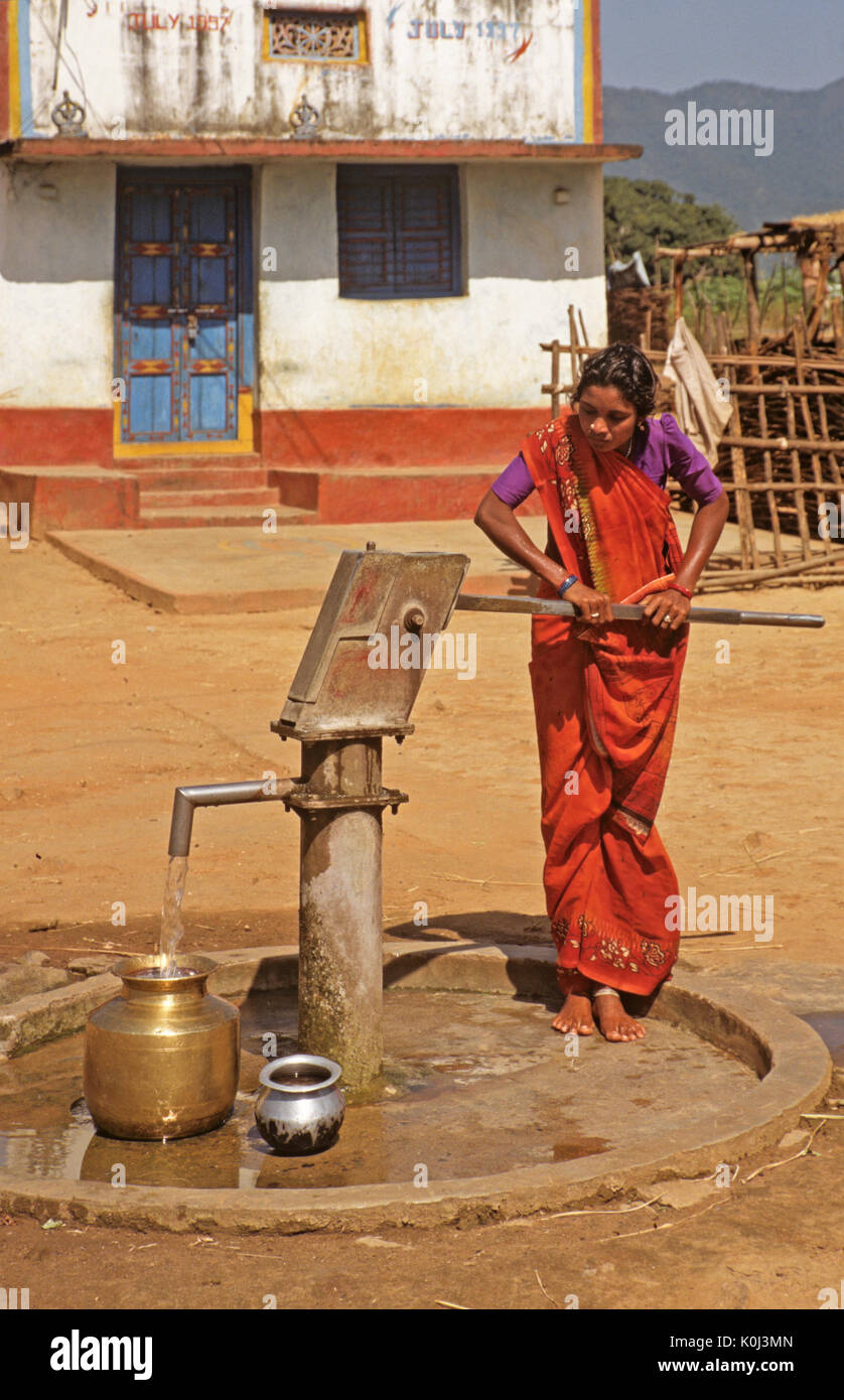 Woman pumping water into pots, Desia Kondh tribal village, Odisha (Orissa), India Stock Photo