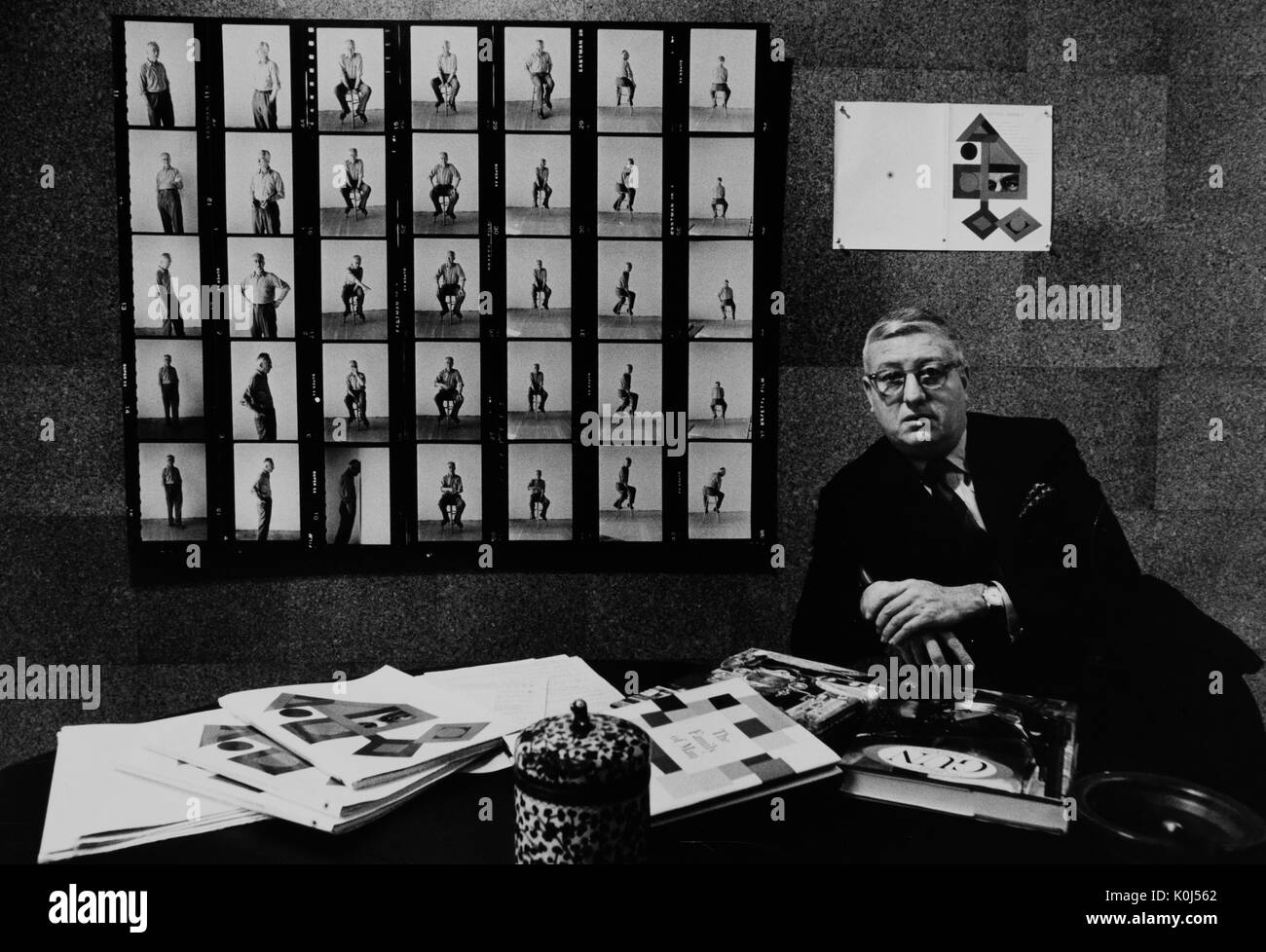 Candid half-length portrait of Jerome Irvin Myerberg Mason in his office with a contact sheet behind him. 1963. Stock Photo
