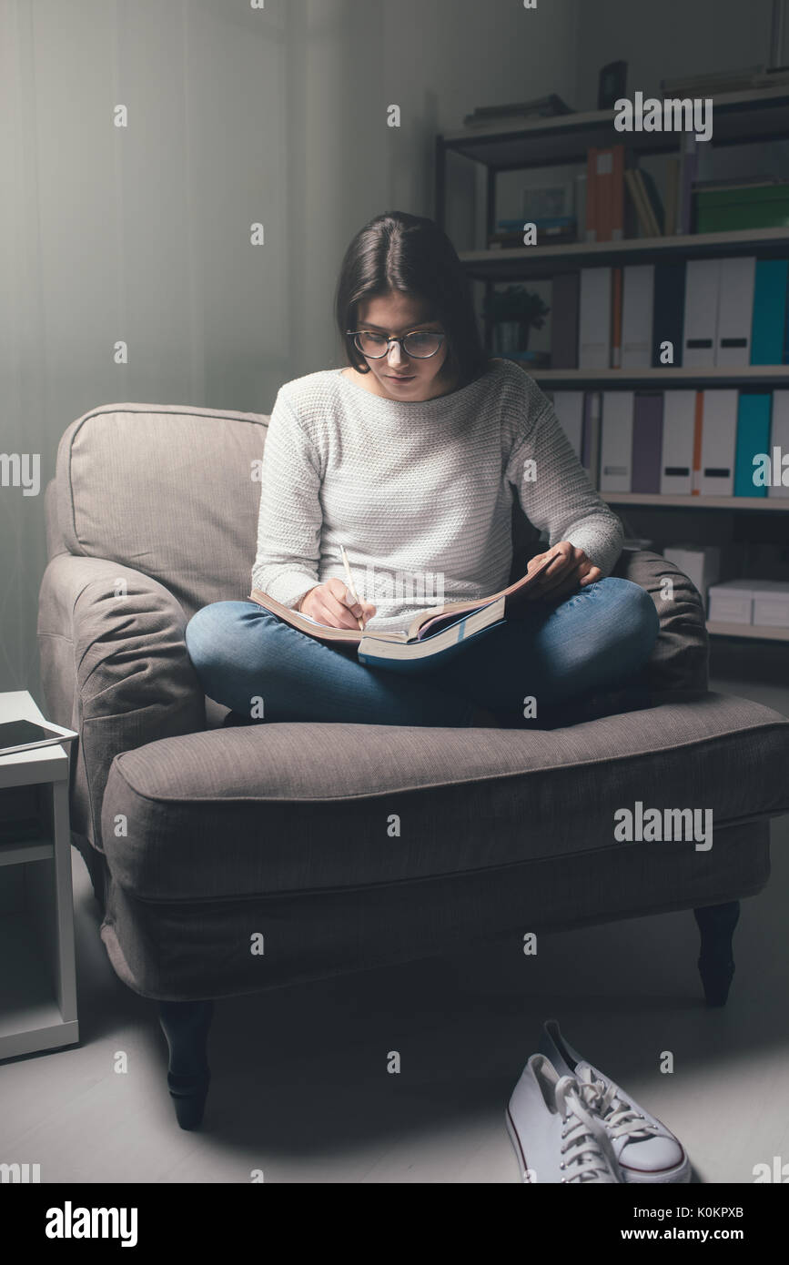 Young woman studying late at night at home, she is sitting on the