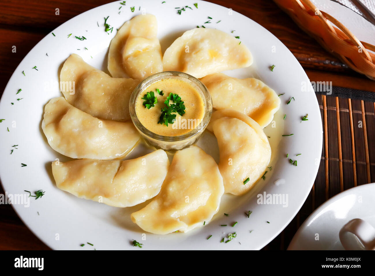 Ukrainian and Russian dish vareniki with mashed potatoes and sour cream and mushroom sauce on white plate. Close up. Stock Photo