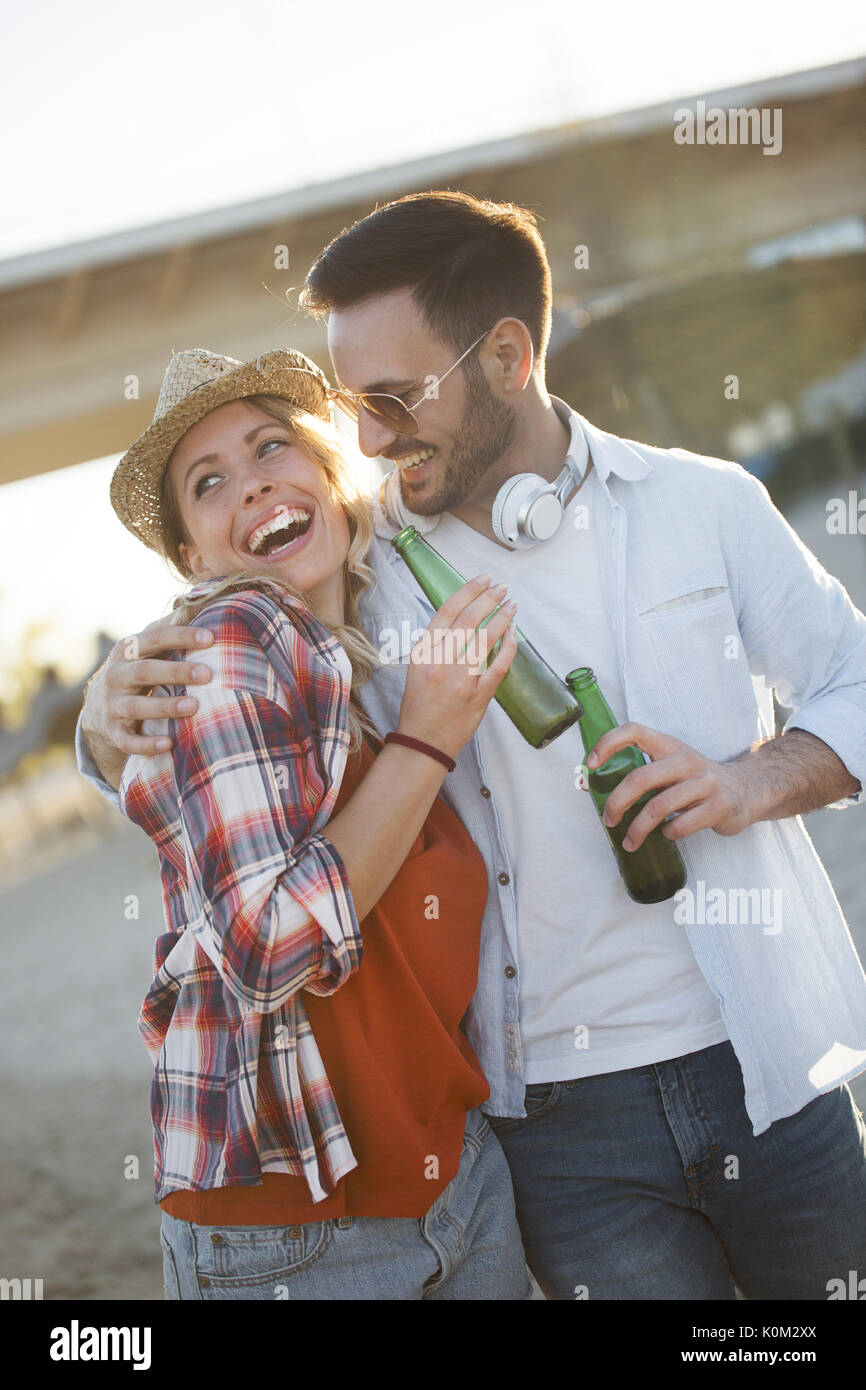 Happy couple smiling and drinking beer at beach Stock Photo