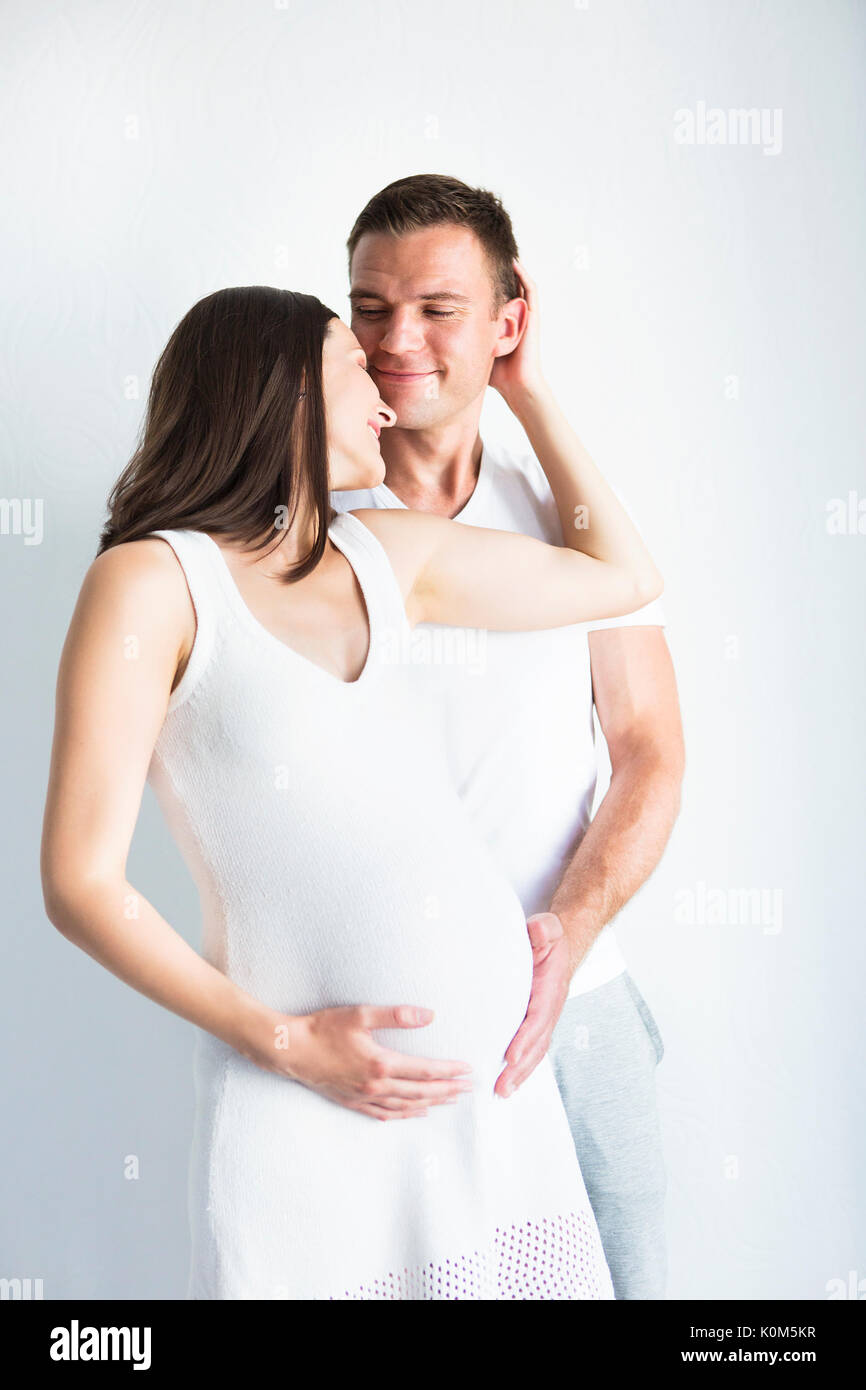 Young man and pretty pregnant woman hugging together indoors Stock ...