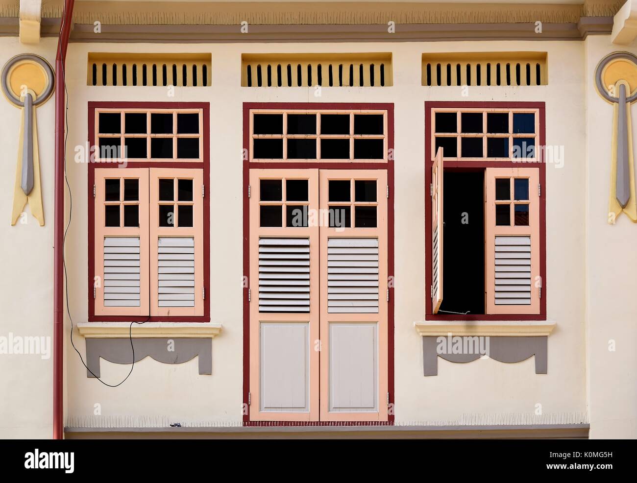 Traditional Chinese shop house exterior with pink wooden louvered shutters and white facade in the Joo Chiat District of Singapore Stock Photo