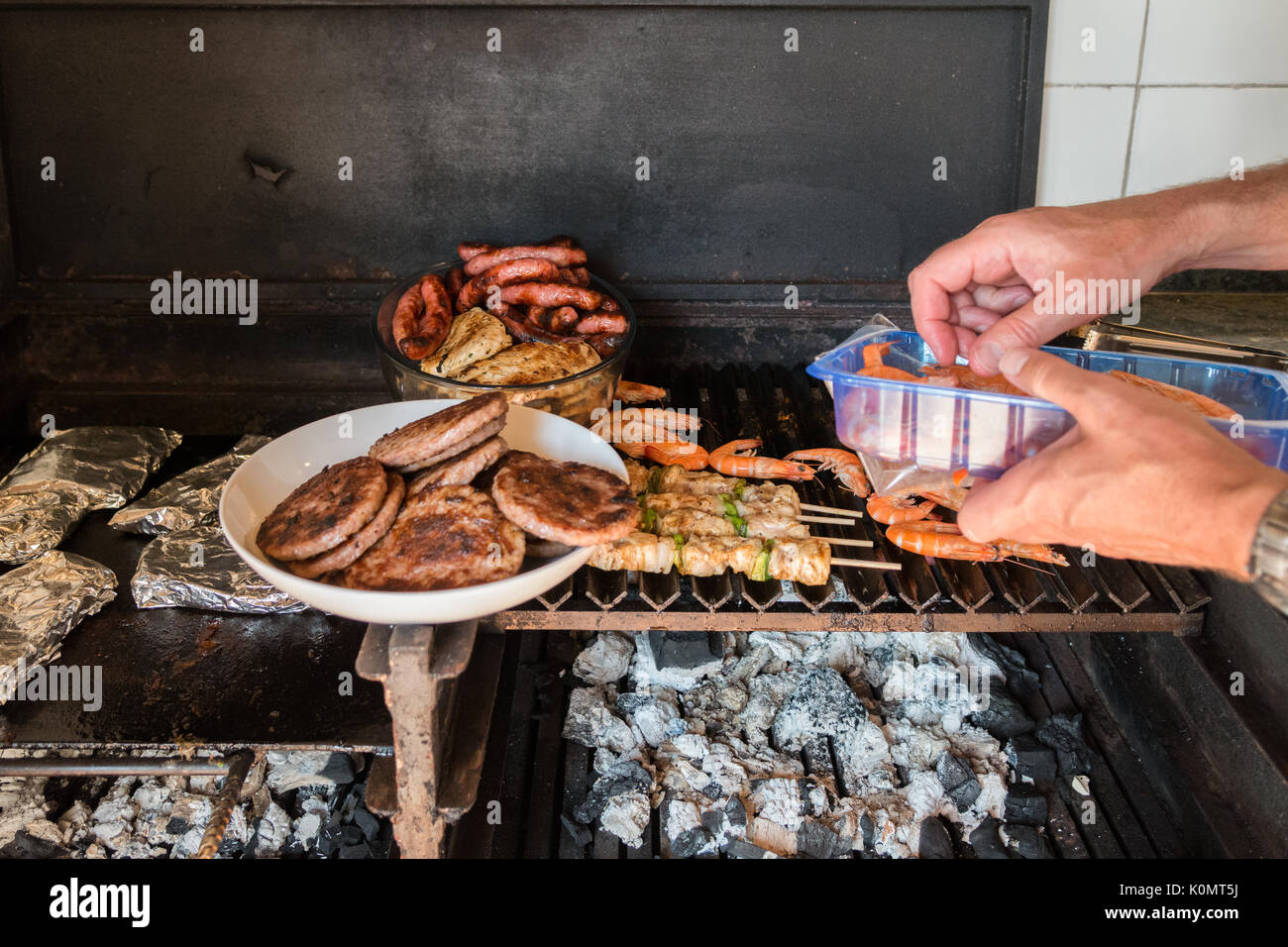adding prawns to a mixed barbecue Stock Photo