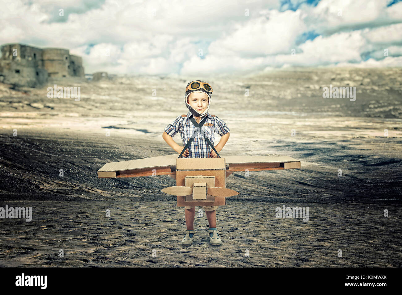 portrait of kid acting like aviator with cardboard airplane desert background Stock Photo