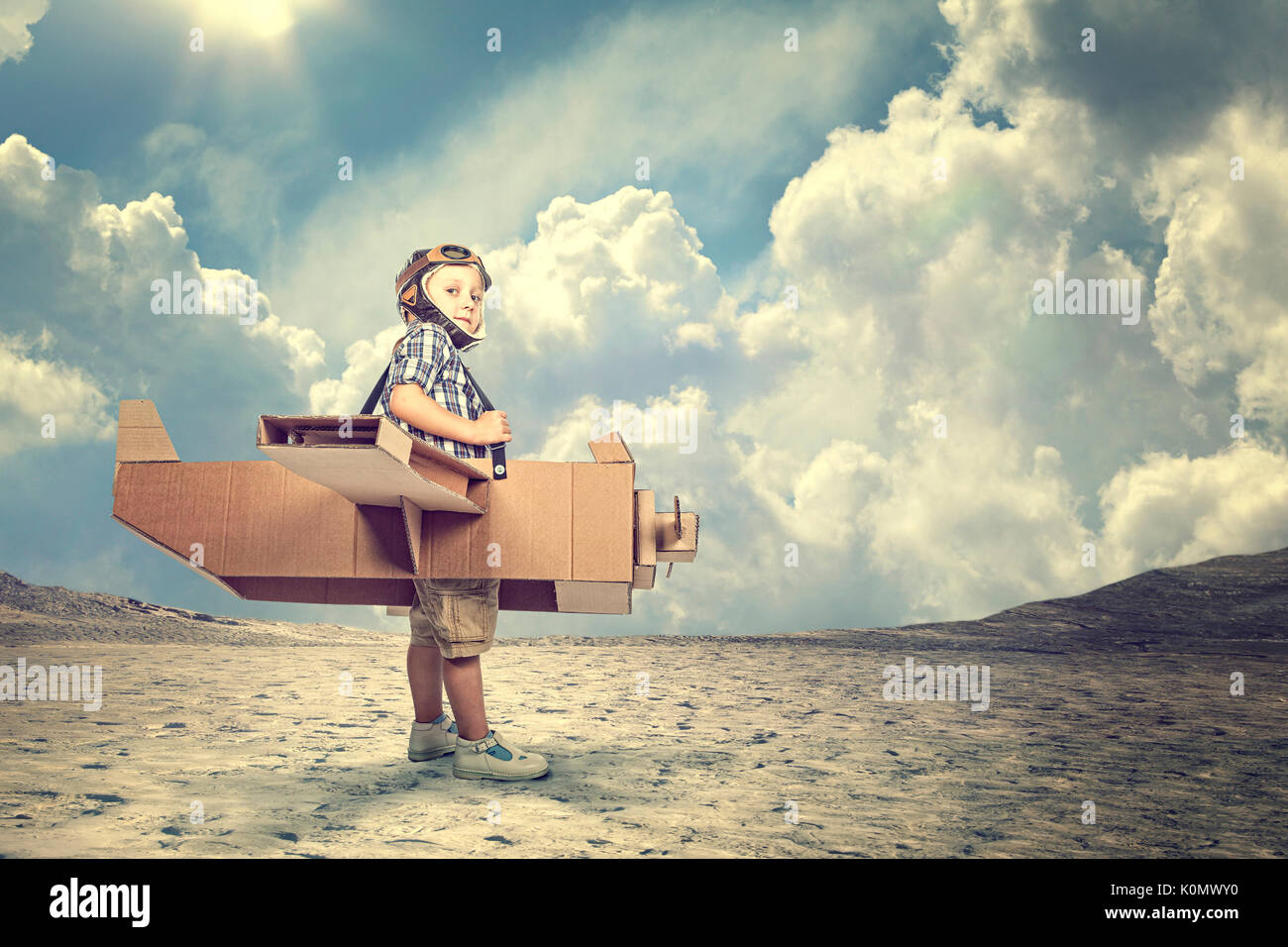 portrait of child play with cardboard airplane in a desert Stock Photo