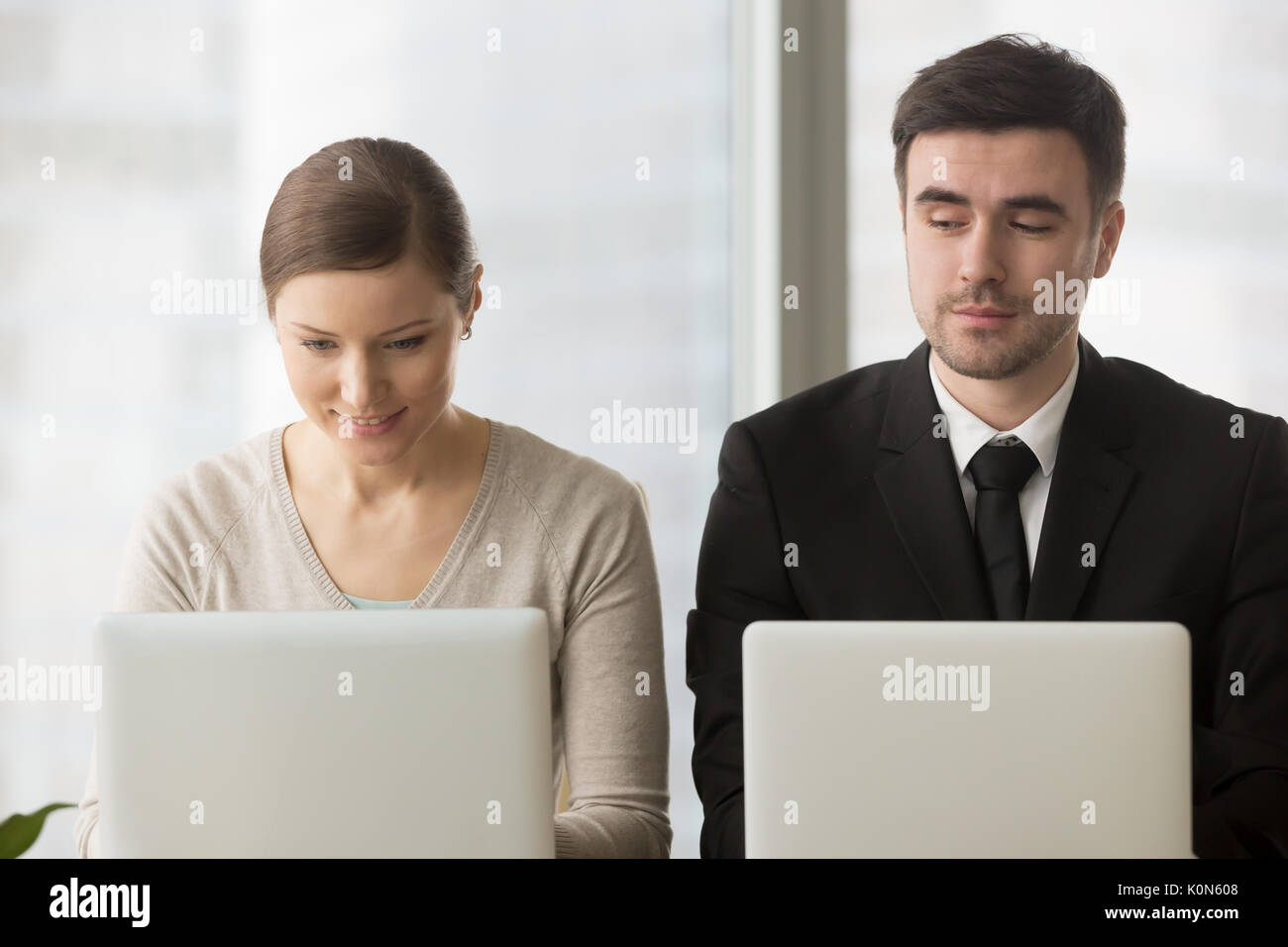 Inquisitive competitor sneakily stealing idea, copying work from Stock