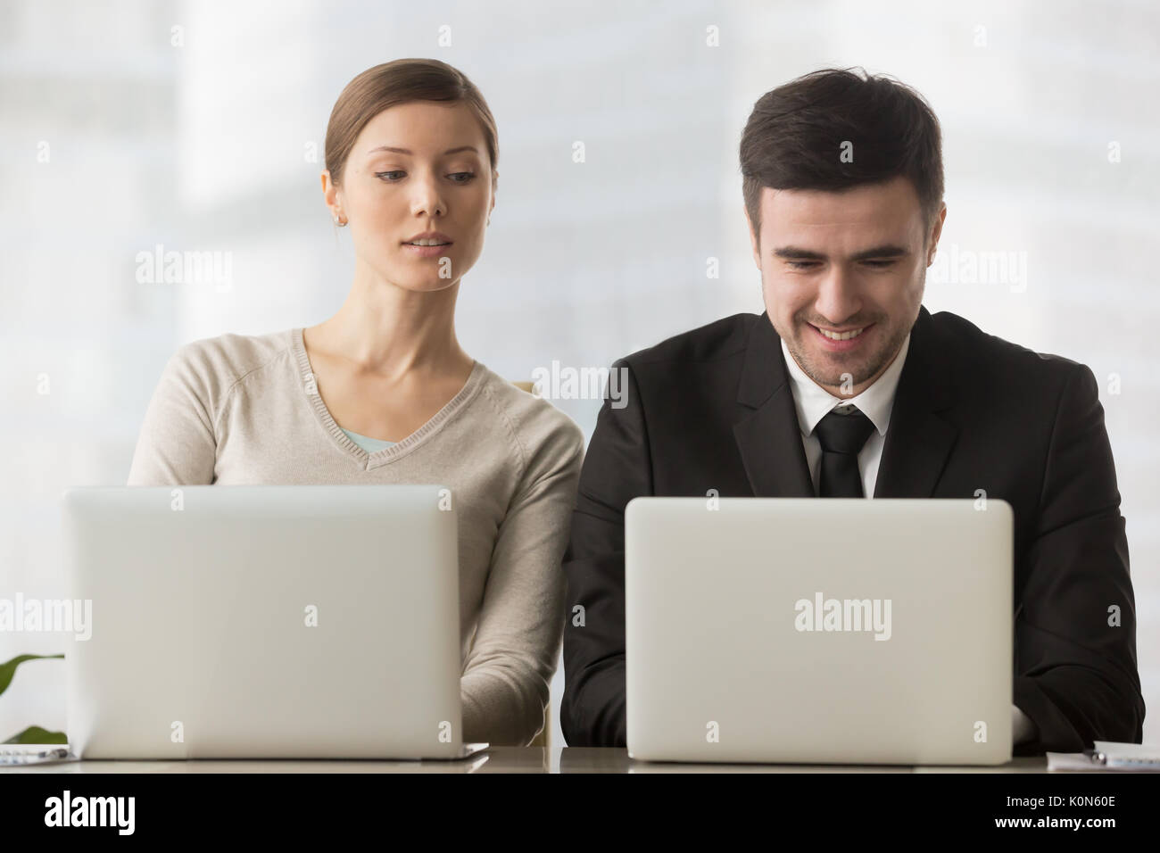 Interested curious businesswoman looking at businessman laptop s Stock Photo