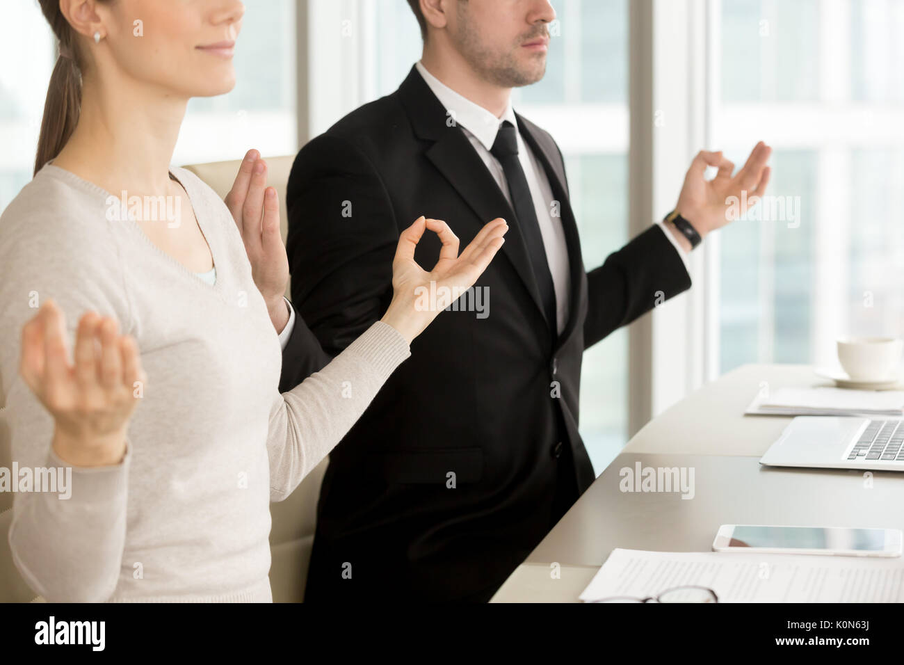 Businessman and businesswoman meditating at office desk, corpora Stock Photo