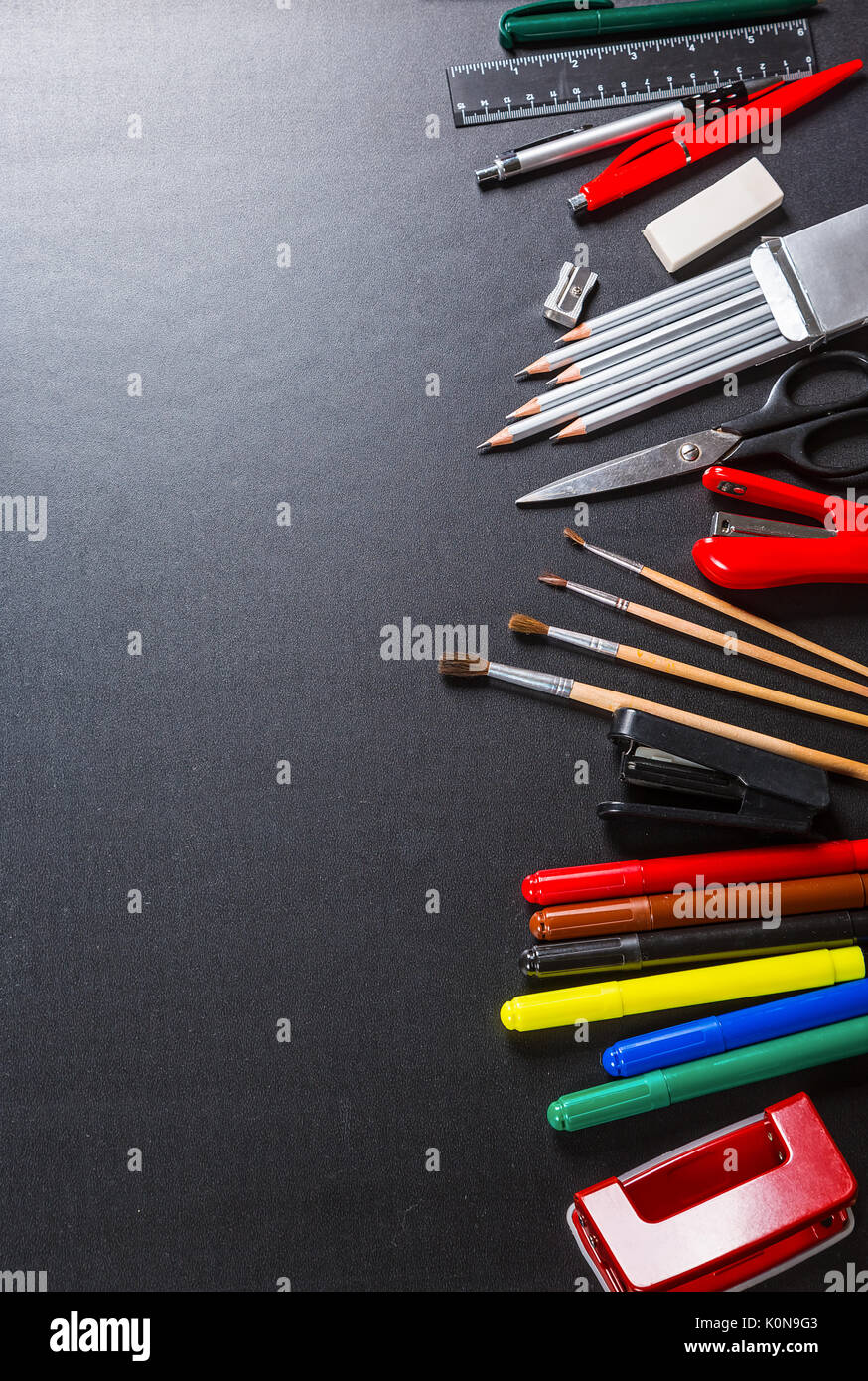 Old blackboard with chalk, stapler, scissors, pencils and stationery. A beautiful backdrop for education, a free space for your text. Back to school. Stock Photo