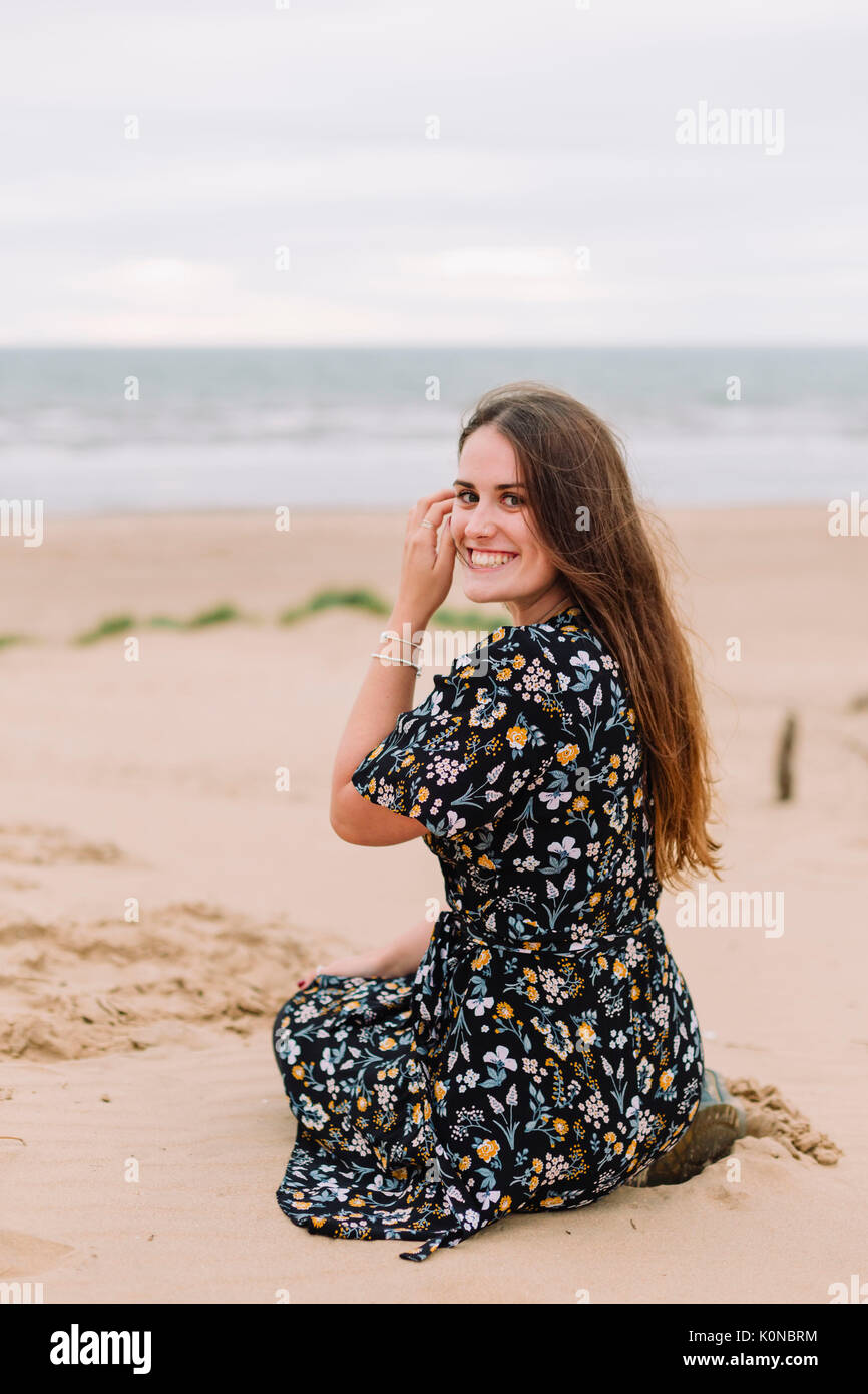 Portrait of happy young woman sitting on the beach Stock Photo - Alamy