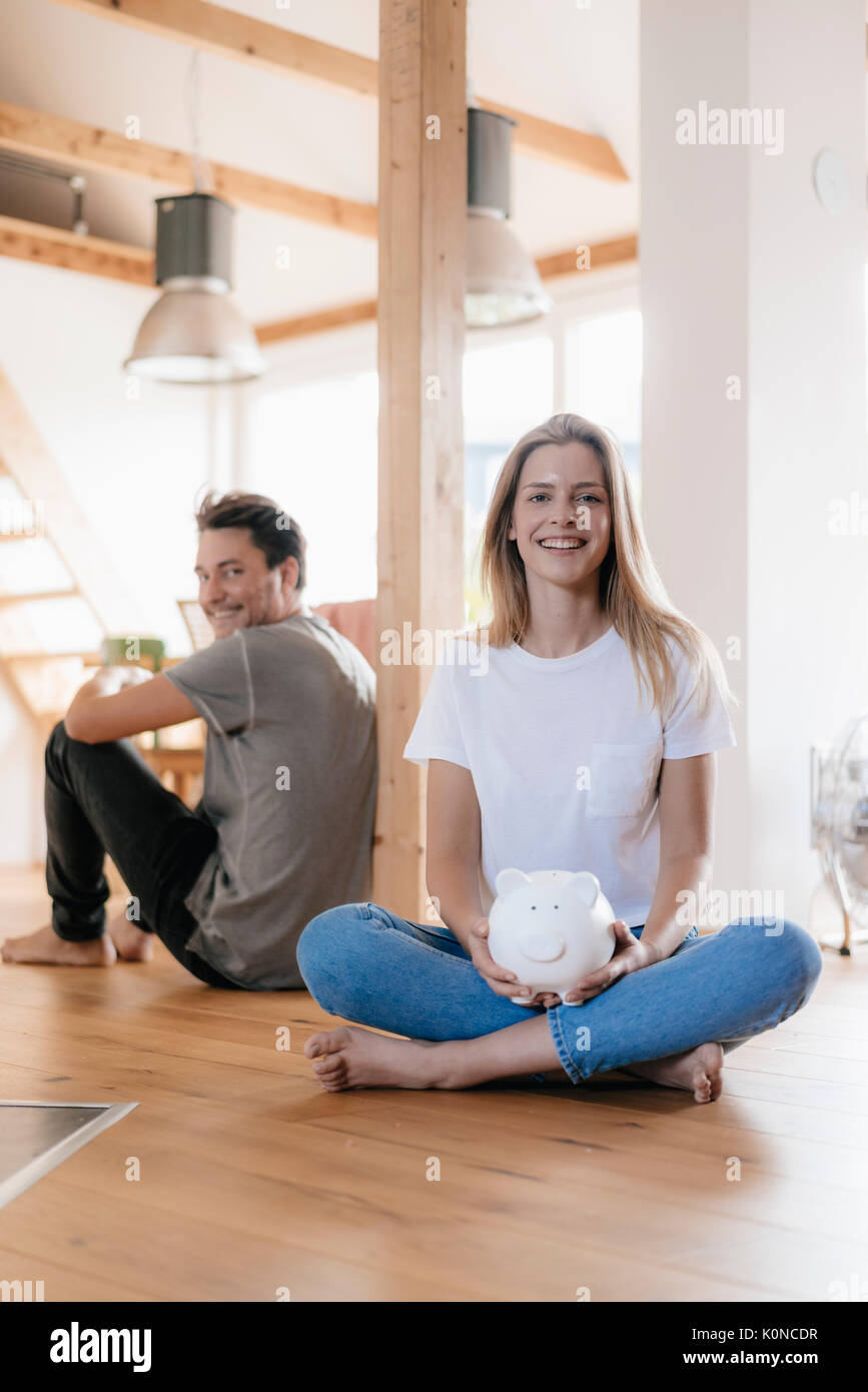 Couple sitting in new home with a piggy bank Stock Photo - Alamy