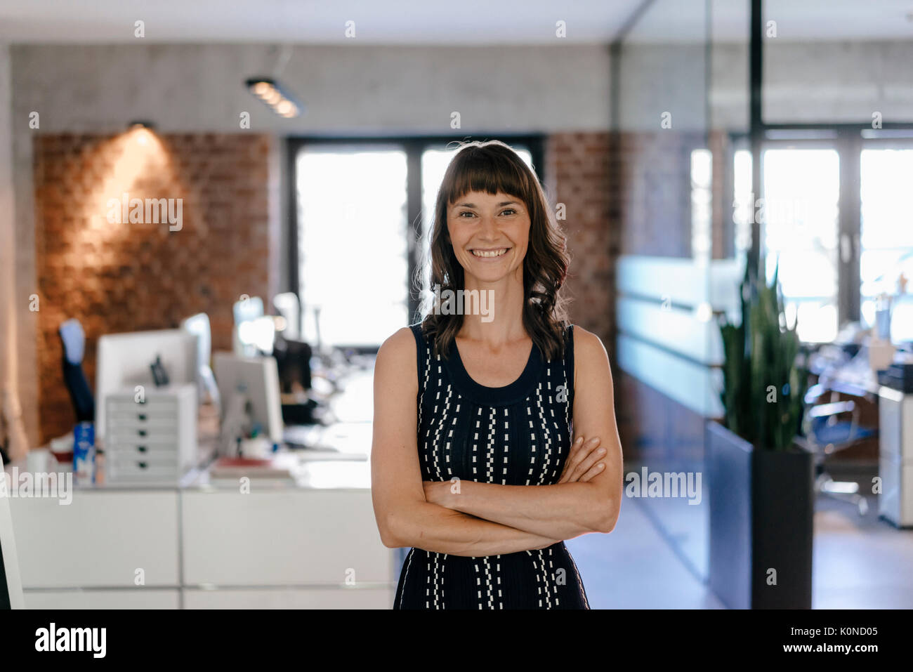 Businesswoman standing in office with arms crossed Stock Photo - Alamy