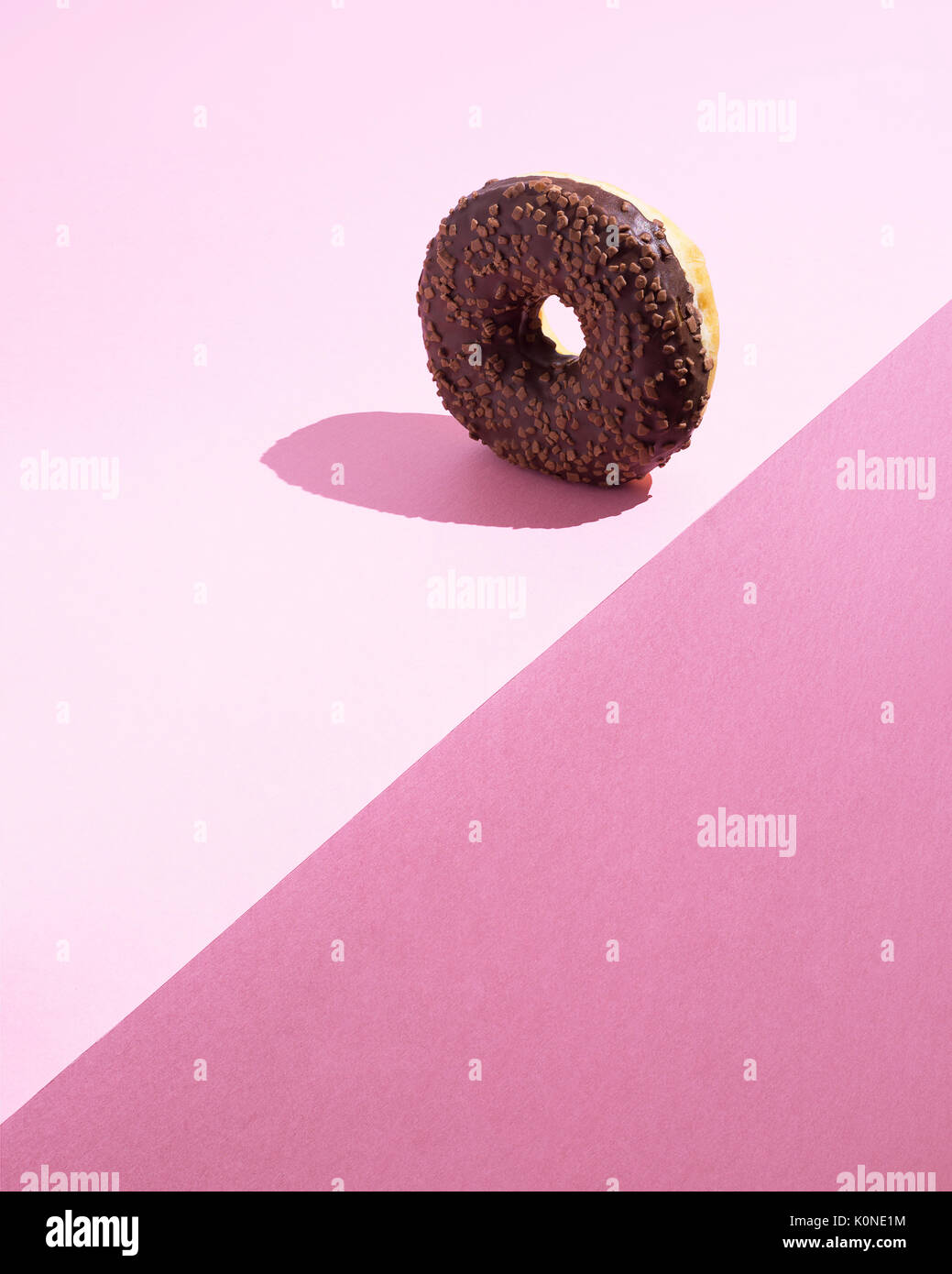 Doughnut with chocolate icing on pink ground Stock Photo