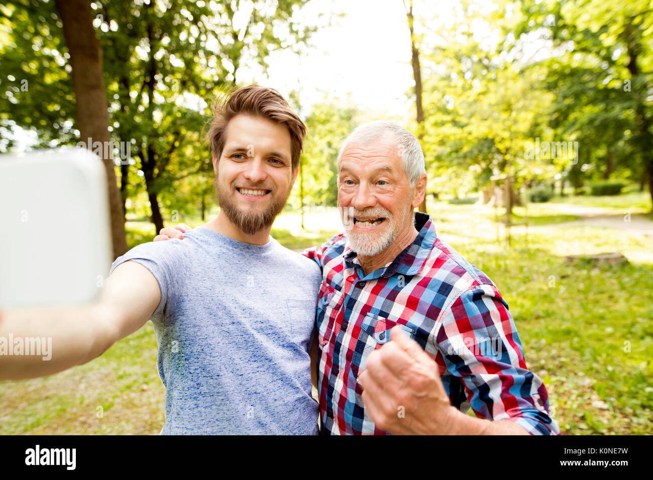 Portrait of senior father and his adult son taking selfie in a park ...